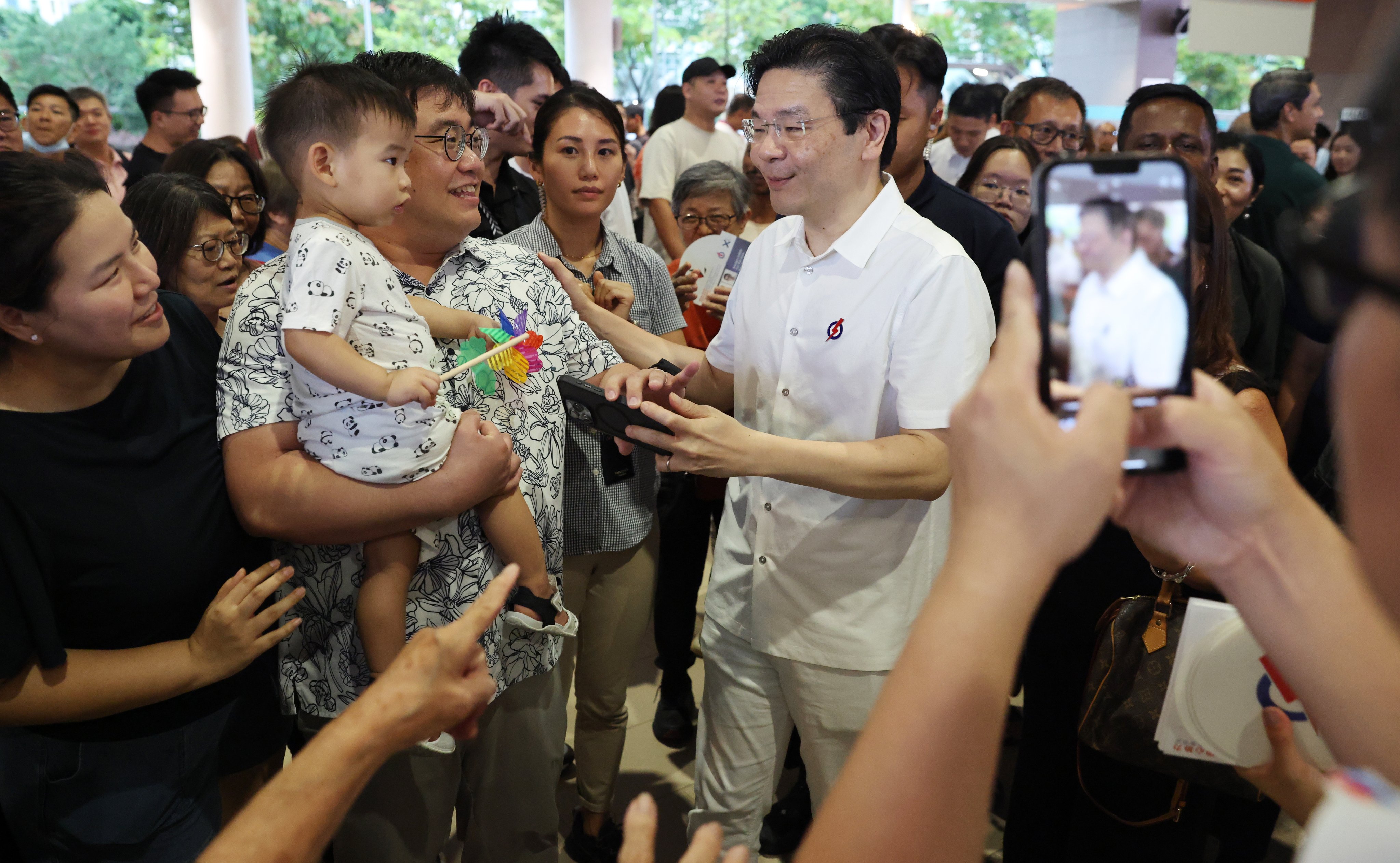 Singapore’s Prime Minister Lawrence Wong (right) greets residents during a campaign walkabout. Photo: EPA-EFE