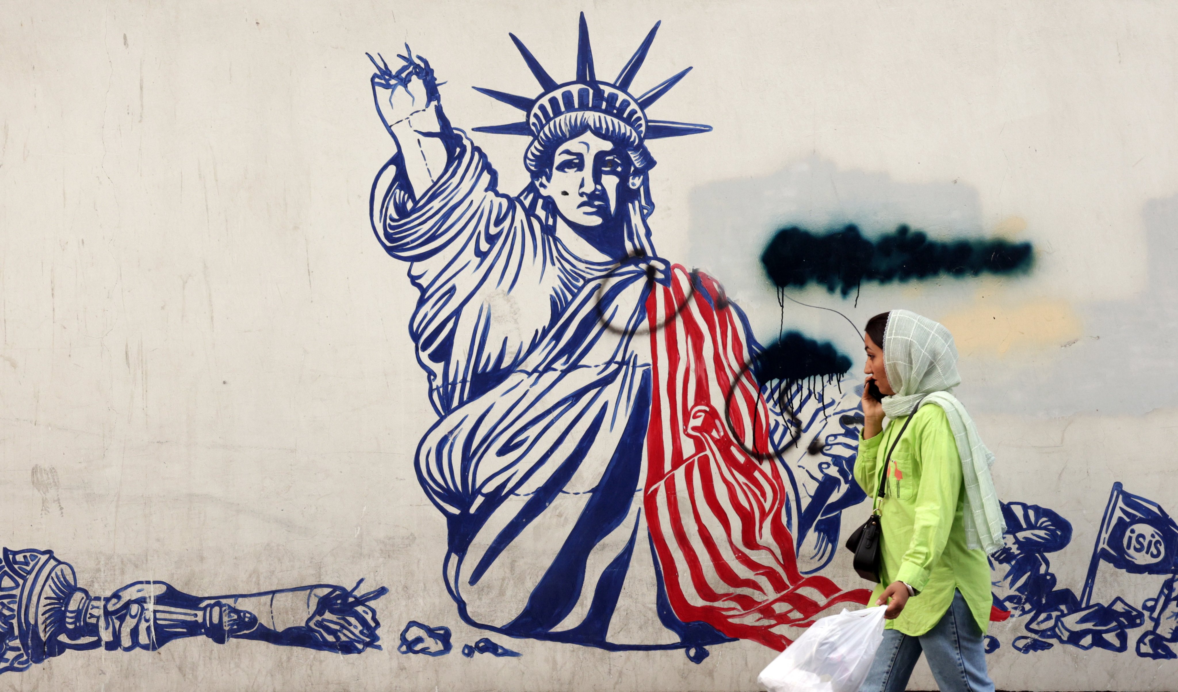 An Iranian woman walks past an anti-US mural near the former US embassy in a street in Tehran, Iran, on Thursday. Photo: EPA-EFE