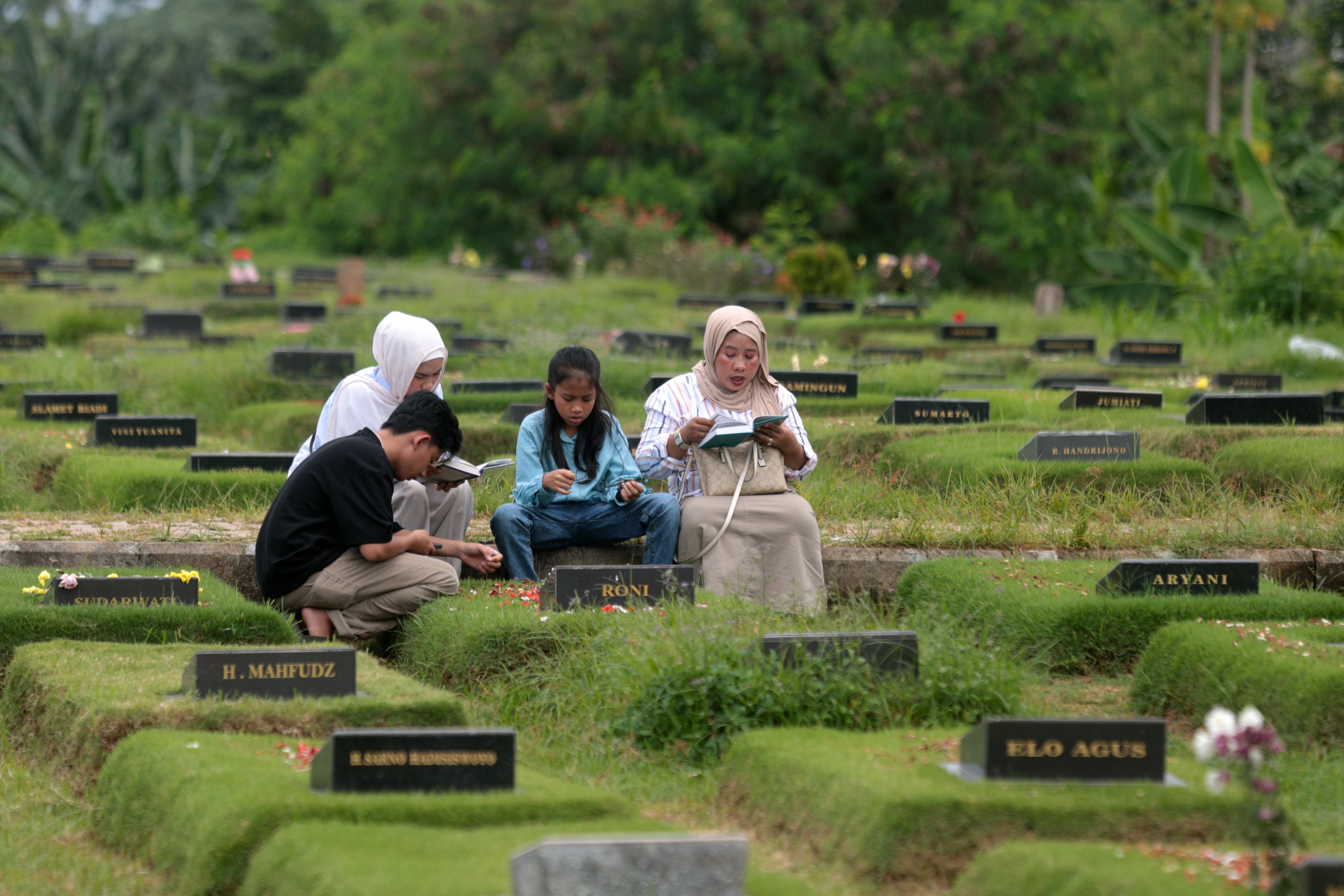 People read the Koran over their relative’s grave at a Covid-19 cemetery on the second day of Eid ul-Fitr in Jakarta on April 1. Photo: EPA-EFE
