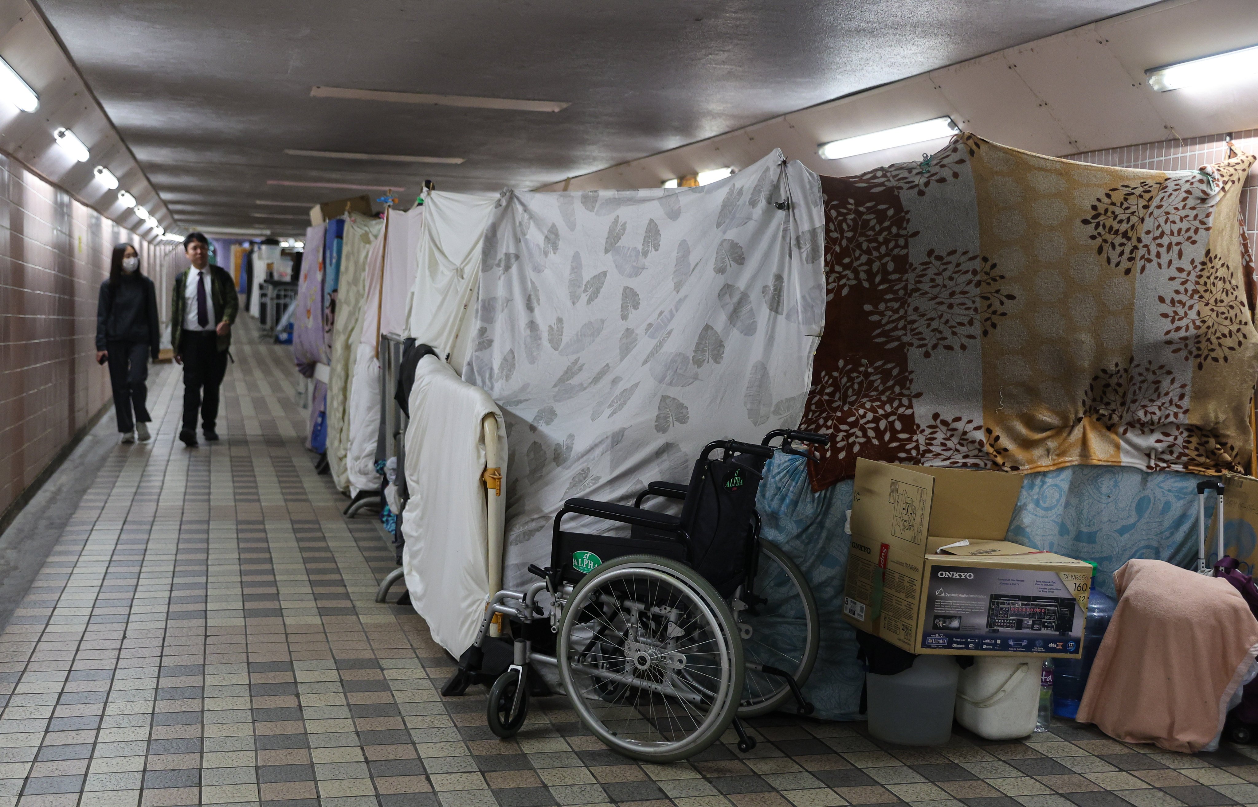 People walk past a few street sleepers’ makeshift dwellings in a subway tunnel in Happy Valley. Photo: Edmond So