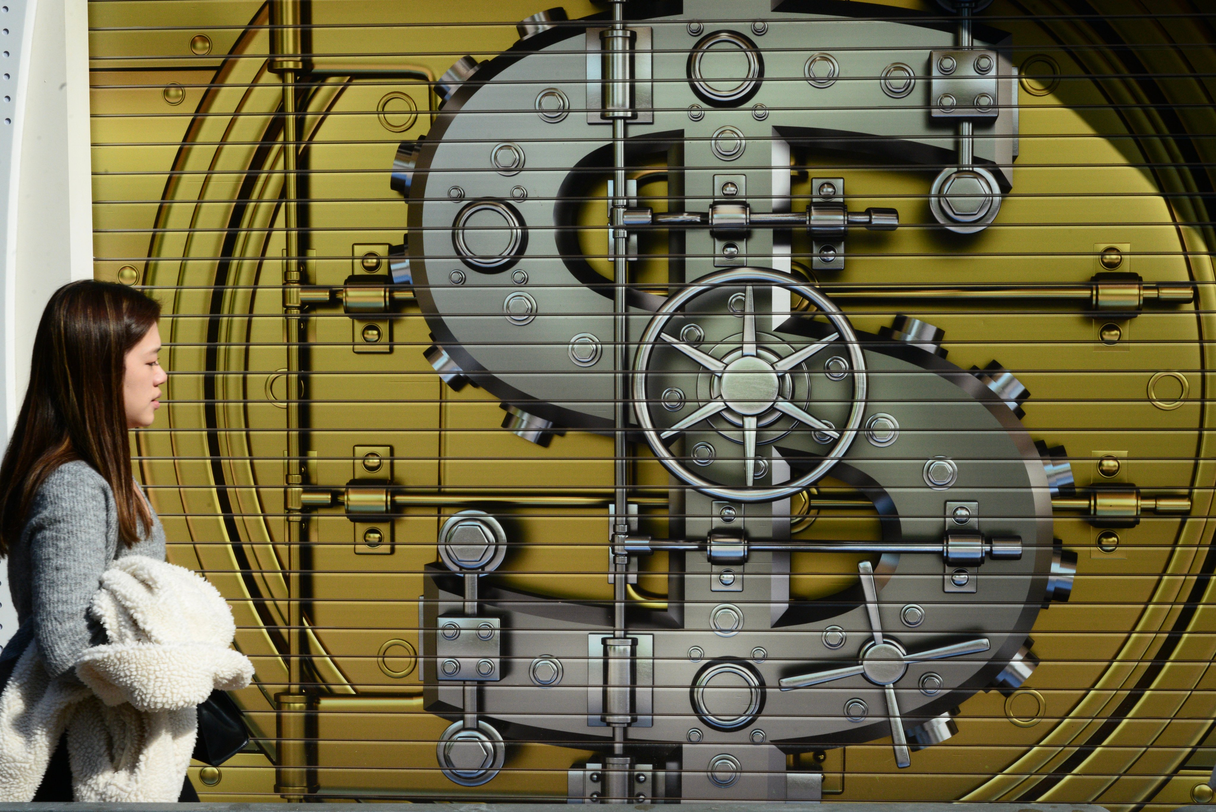 A pedestrian in front of a currency mural on a shop’s gate in Hong Kong on 26 December 2024. Photo: Antony Dickson