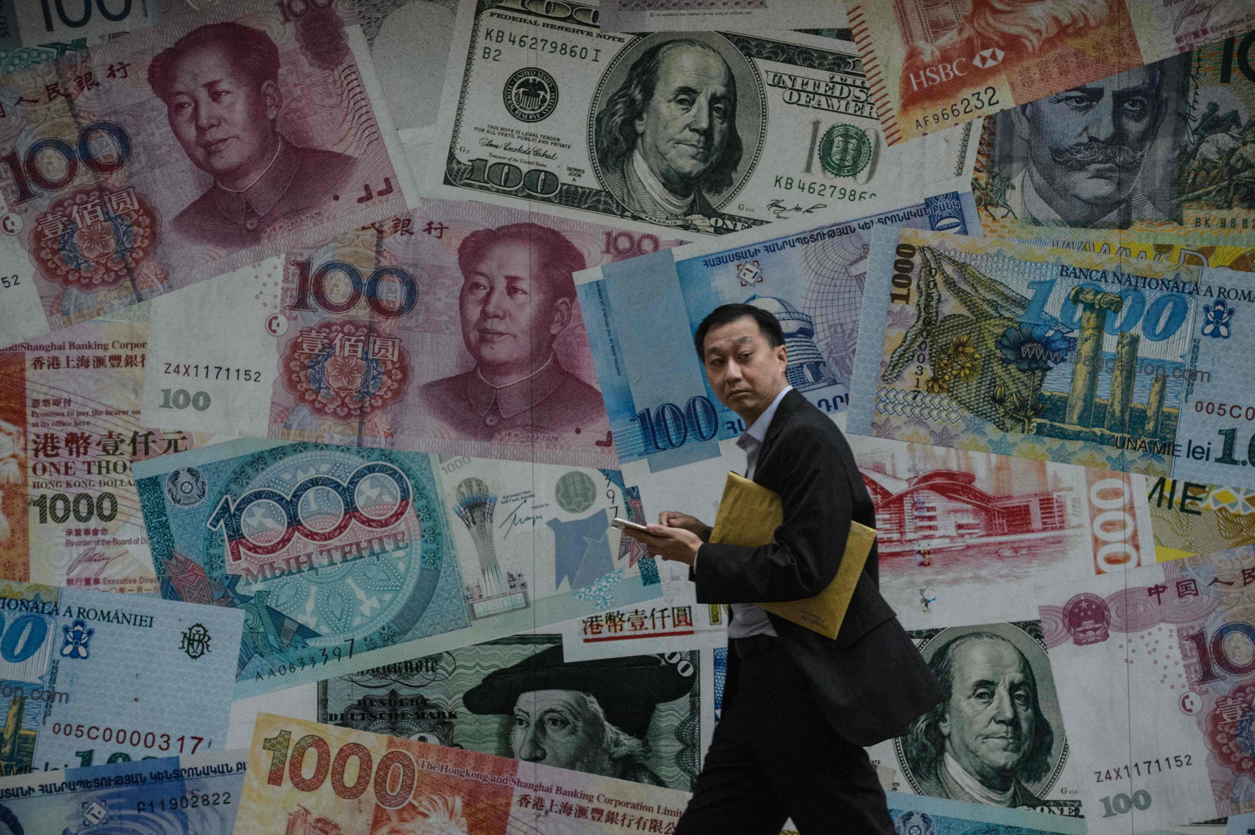 A man walks past a display showing bank notes of different currencies in Hong Kong on November 9, 2016. Photo: AFP
