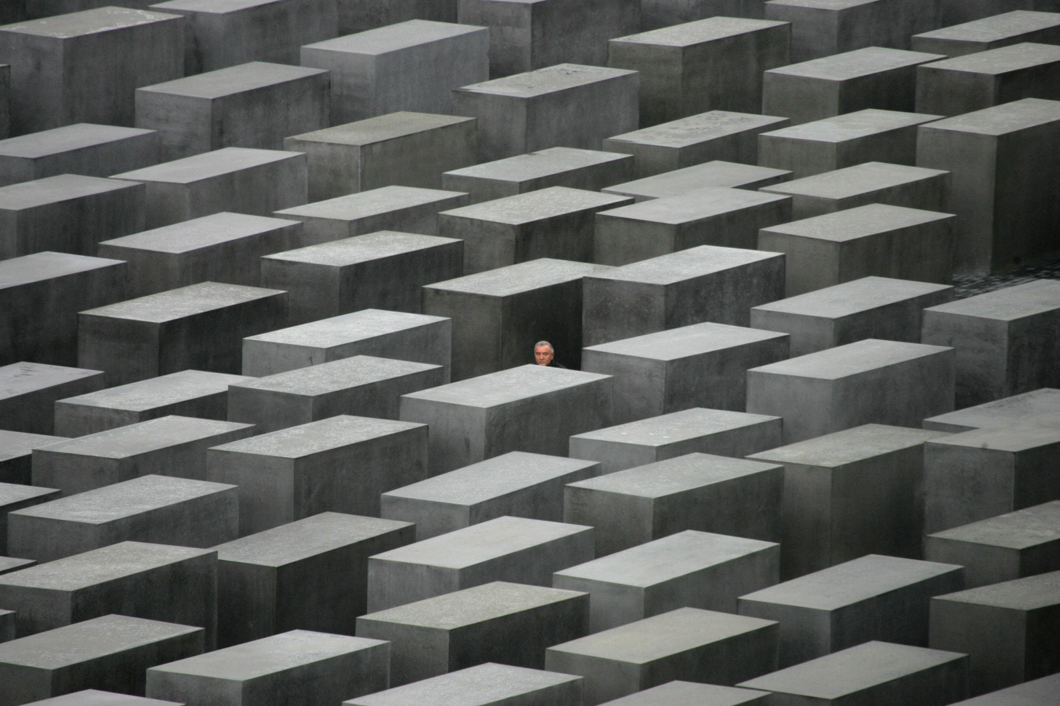 (FILES) A picture taken on May 10, 2005 shows a guest walking through the Memorial for the Murdered Jews of Europe following the memorial’s inauguration in Berlin. Some say it feels like walking through a field of gravestones, others liken it to a maze of coffins, disorientating and eerily quiet despite being in the middle of Berlin. The German capital’s sombre Holocaust memorial -- an arrangement of 2,711 concrete steles, which has drawn millions of visitors -- marks its 20th anniversary on May 10, 2025.   (Photo by John MACDOUGALL / AFP)