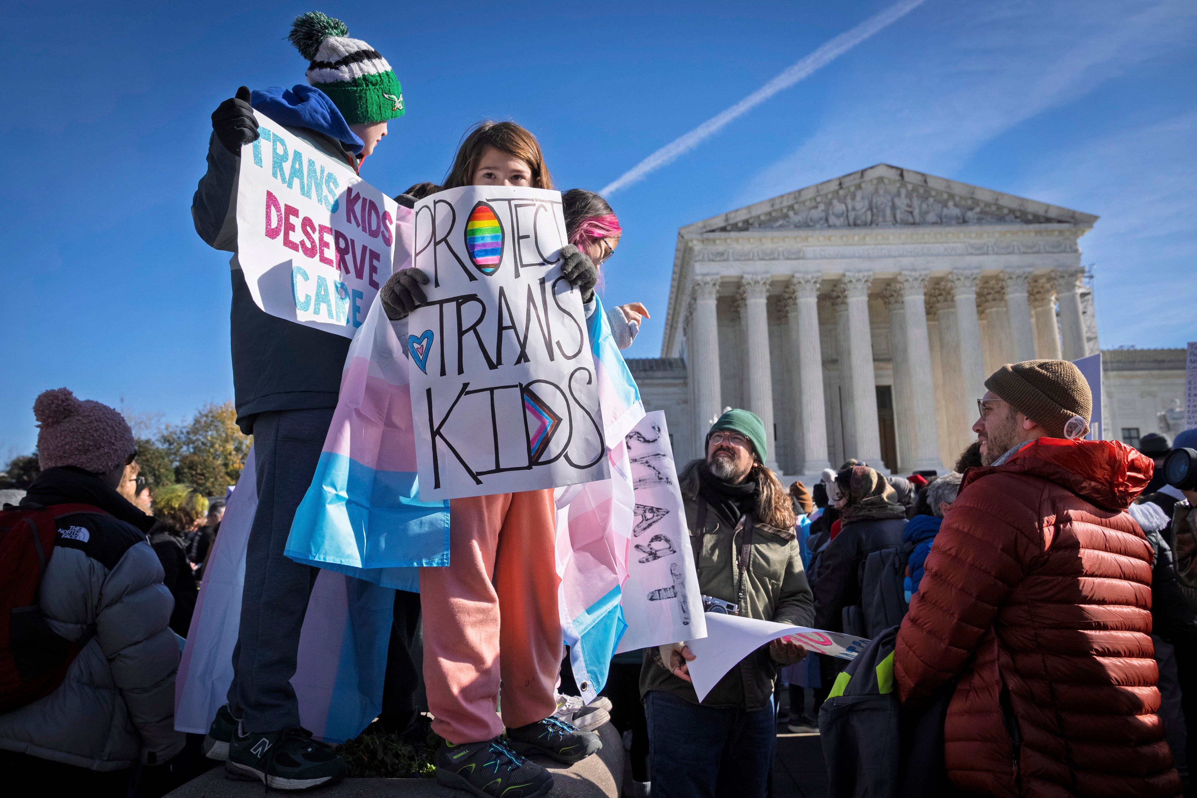 Children hold signs and transgender pride flags as supporters of transgender rights rally by the US Supreme Court in December. Photo: AP