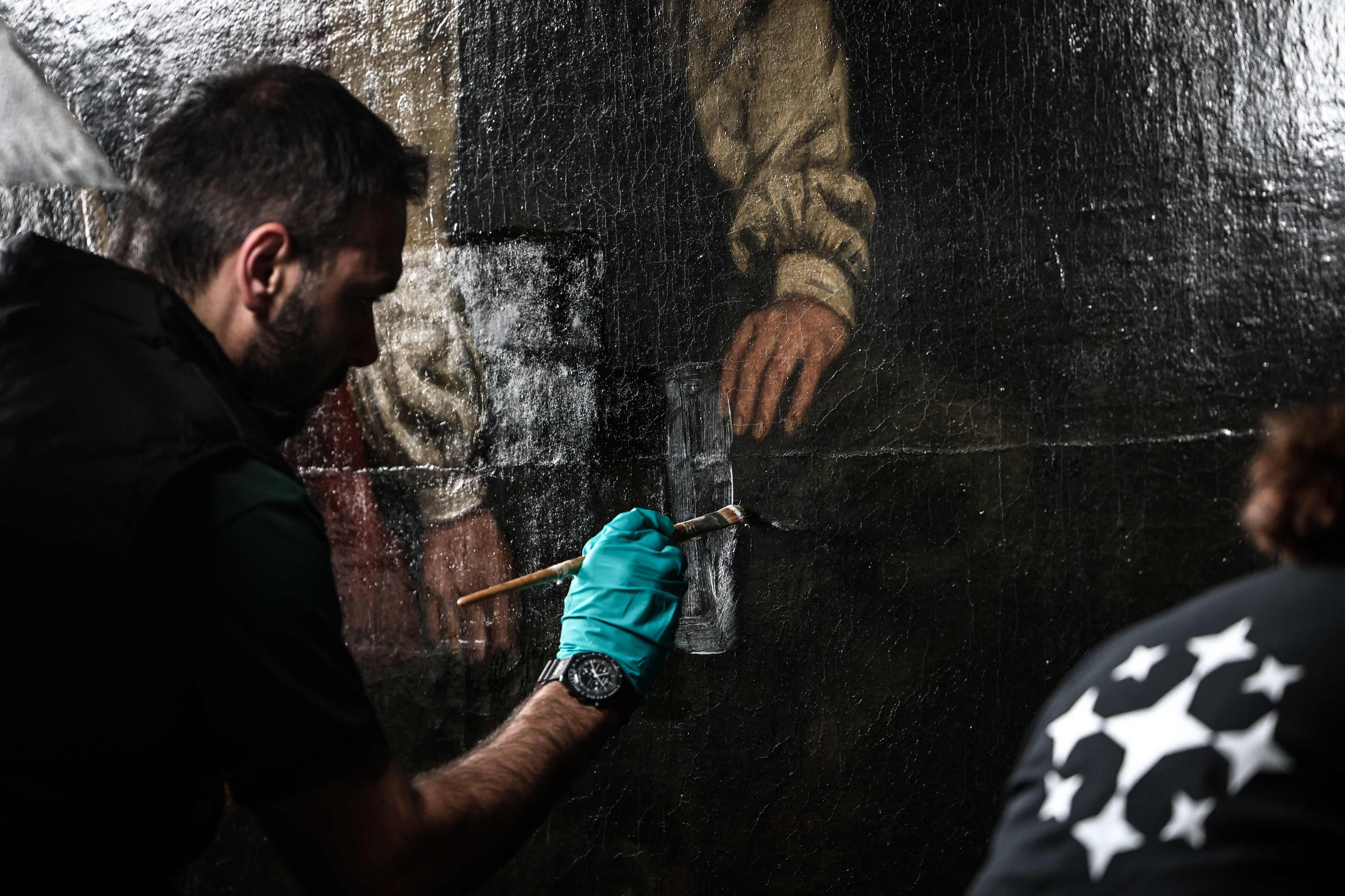 An art restorer carefully removes layers of varnish that have yellowed over time as he works on Gustave Courbet’s painting titled A Burial at Ornans at the Orsay Museum in Paris. Photo: AFP