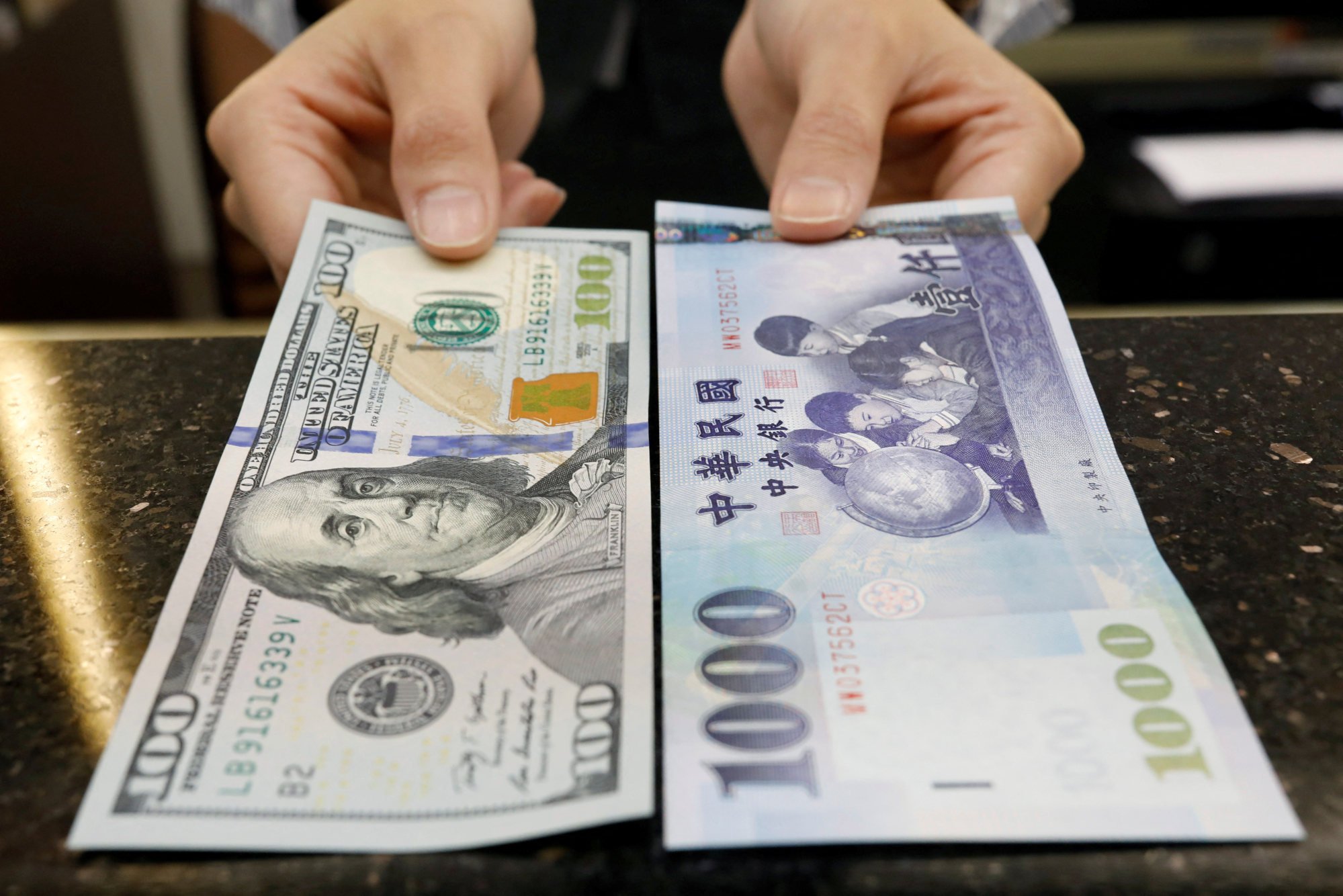 A teller poses with US$100 and NT$1,000 banknotes at a bank in Taipei, Taiwan. Photo: Reuters A teller poses with US$100 and NT$1,000 banknotes at a bank in Taipei, Taiwan. Photo: Reuters