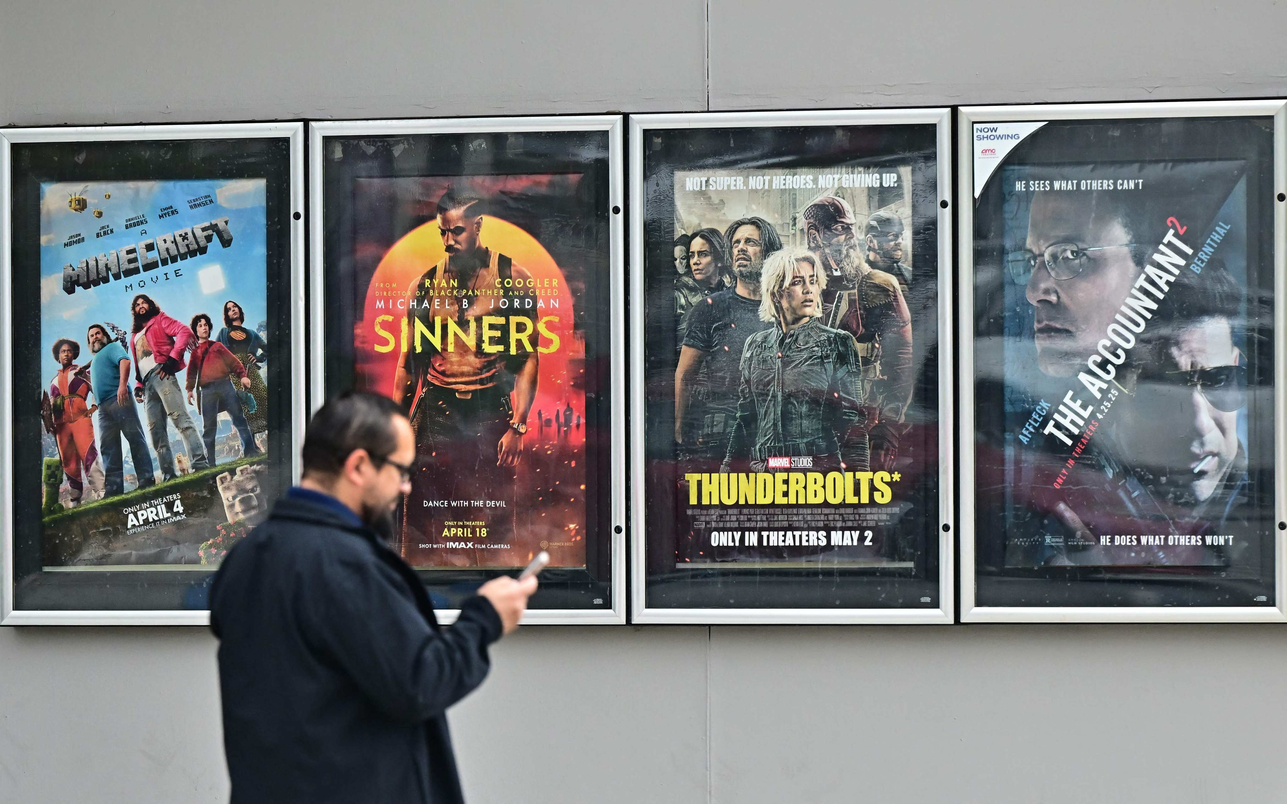 A man walks past movie posters at at AMC Theater in Montebello, California on May 5. US President Donald Trump said he was ordering new tariffs on all films made outside the United States, claiming Hollywood was being “devastated” by a trend of US filmmakers and studios working abroad. Photo: AFP