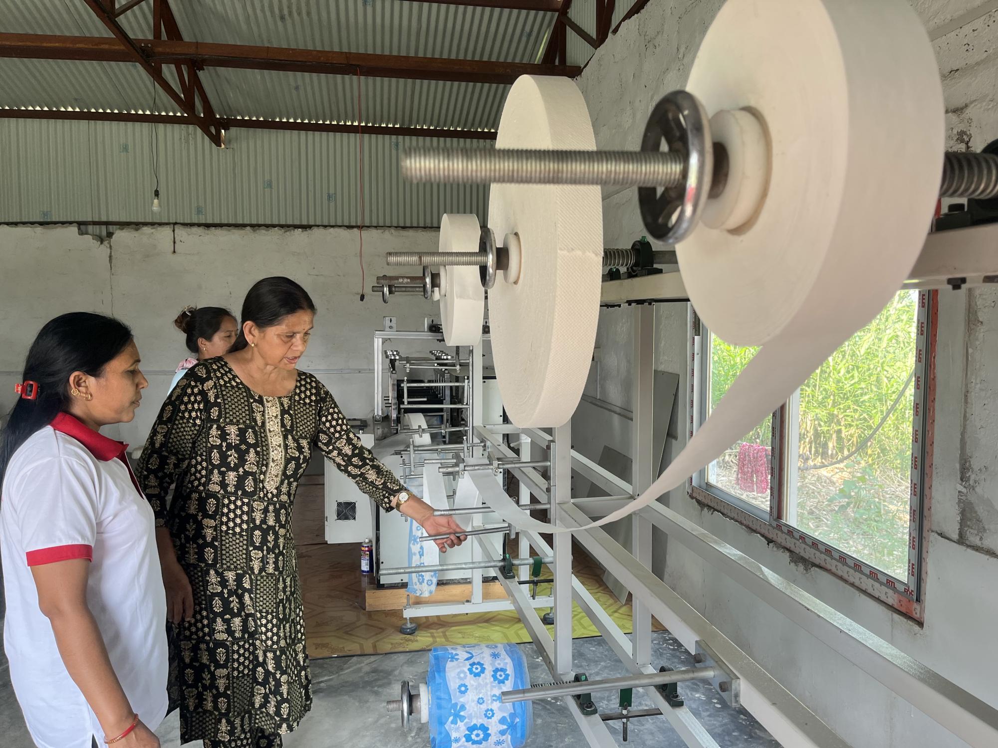 Sabitri Bhandari, coordinator of the Miteri Jaibik Pad Udhyog factory in Chitwan, inspects a pad-making machine. Photo: Bibek Bhandari Sabitri Bhandari, coordinator of the Miteri Jaibik Pad Udhyog factory in Chitwan, inspects a pad-making machine. Photo: Bibek Bhandari