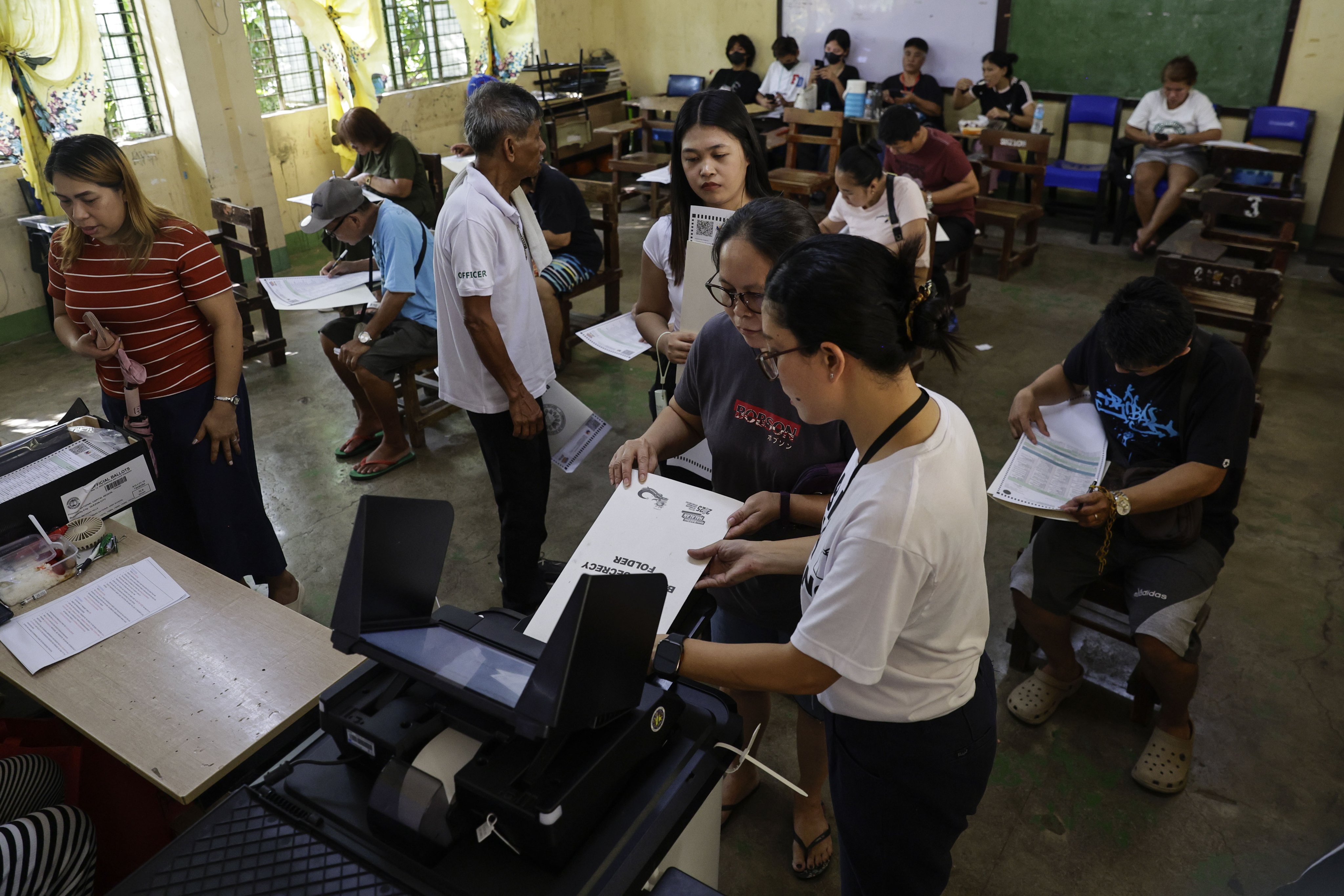 Filipinos feed their ballots into a vote-counting machine at a school used as a voting centre in Quezon City, Metro Manila, Philippines, on Monday. Photo: EPA-EFE