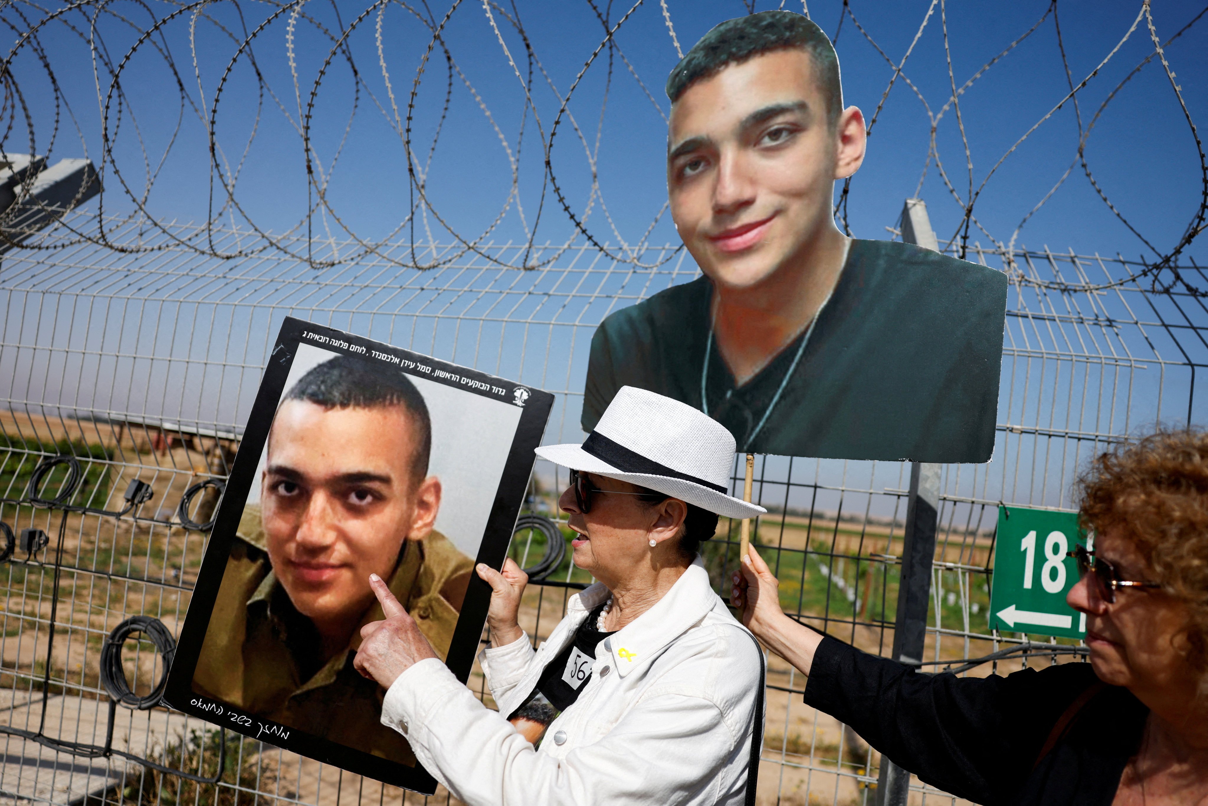 Varda Ben Baruch, grandmother of US hostage Edan Alexander, points at his portrait, as family members and supporters of hostages who were kidnapped during the deadly October 7 attack, stand near the kibbutz defence on the day they use giant loudspeakers to call their captive loved ones over the border between Israel and Gaza, at Kibbutz Nir Oz, in southern Israel, April 20, 2025. REUTERS/Amir Cohen     TPX IMAGES OF THE DAY