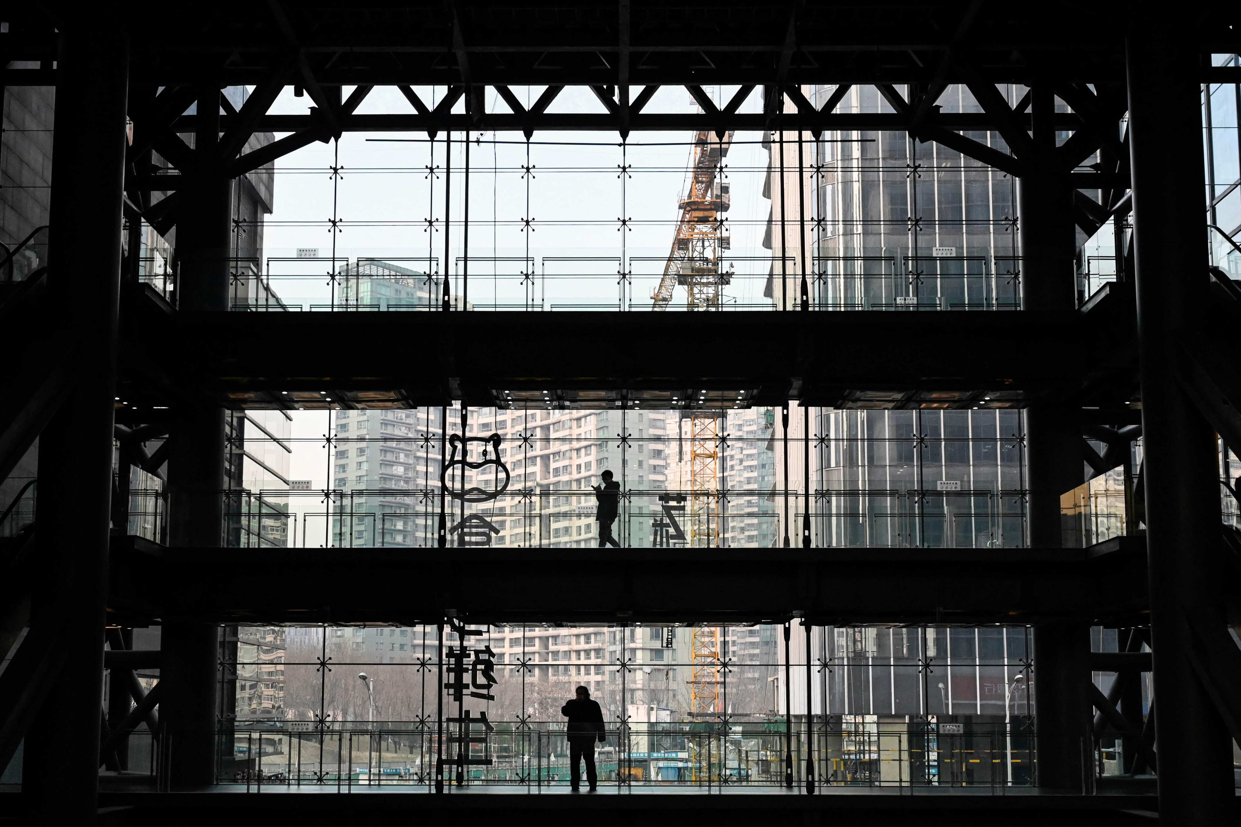 People are silhouetted in an office building in Beijing. Photo AFP