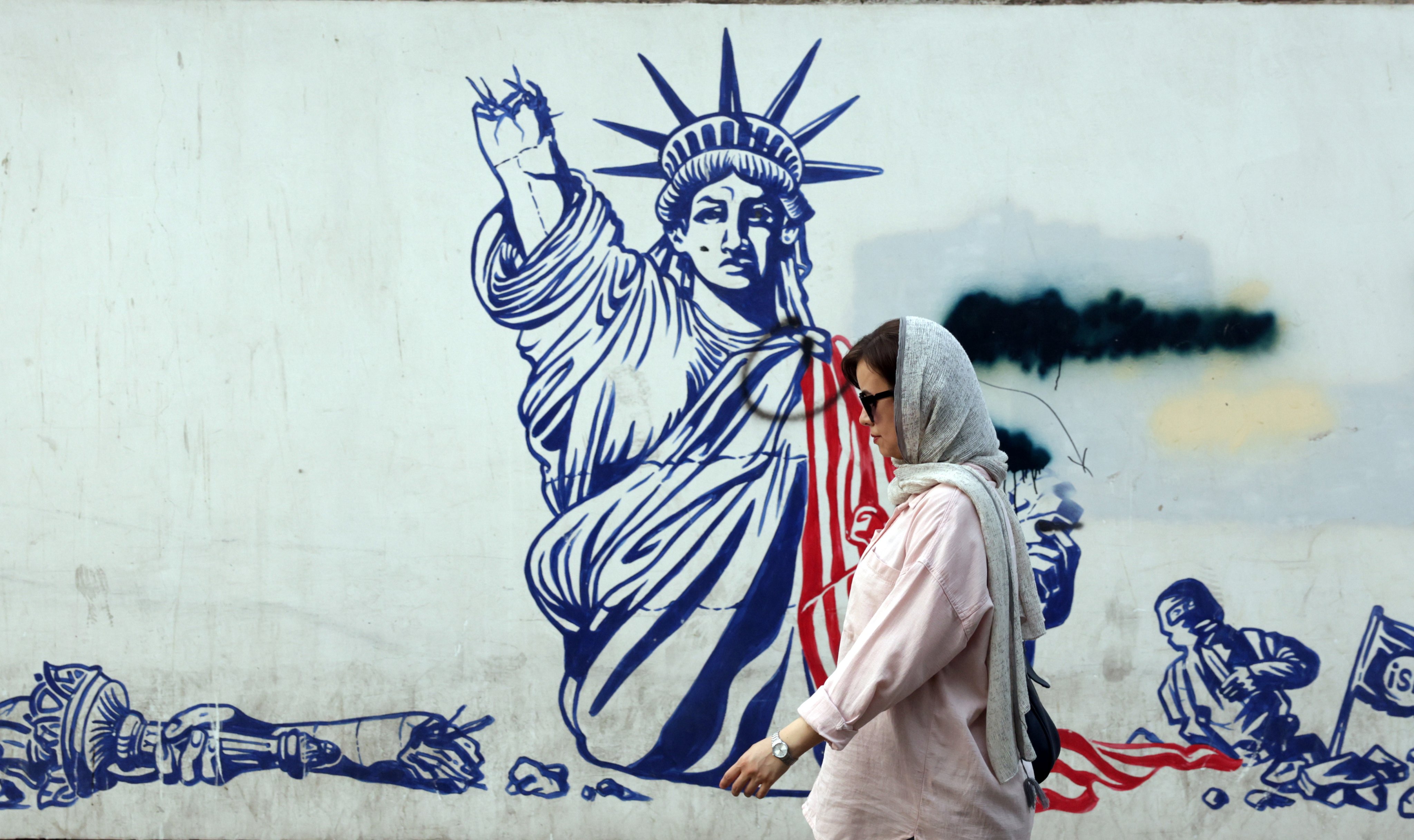 An Iranian woman walks past an anti-US mural near the former US embassy in Tehran. Photo: EPA-EFE