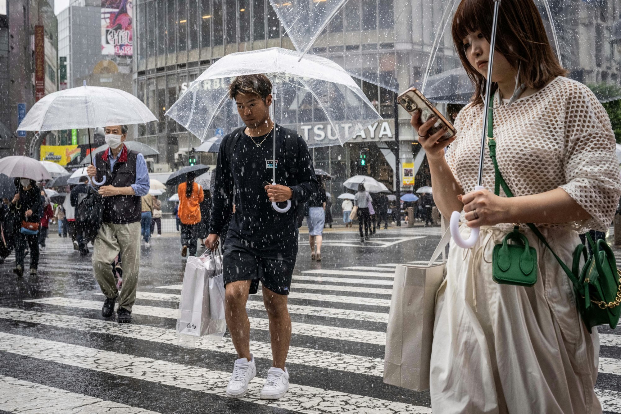 A woman looks at her phone as people use umbrellas to shelter from the rain in Tokyo’s Shibuya district. Photo: AFP A woman looks at her phone as people use umbrellas to shelter from the rain in Tokyo’s Shibuya district. Photo: AFP