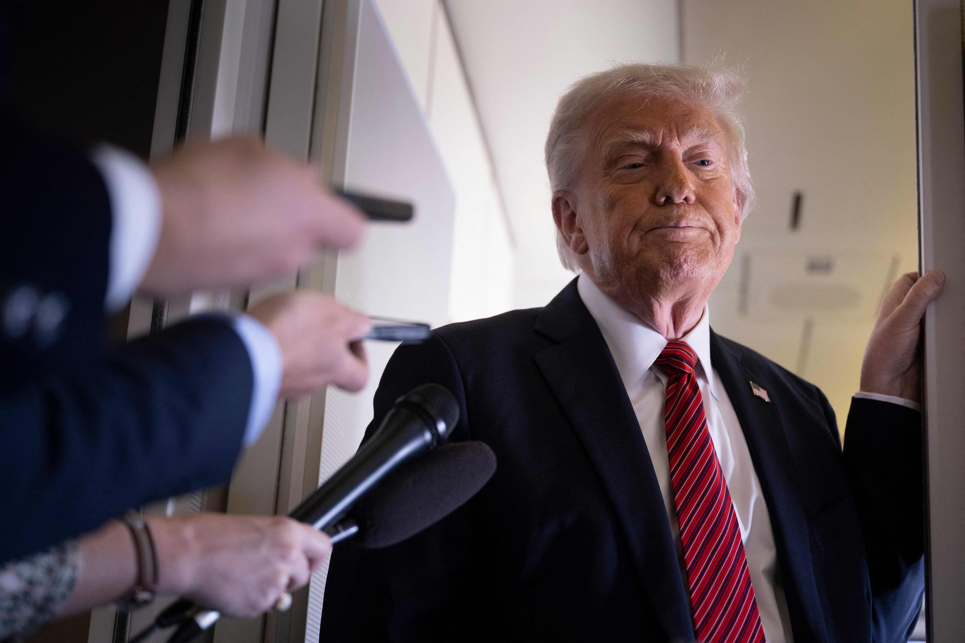 US President Donald Trump listens to questions as he speaks to members of the press on Air Force One on Wednesday. Photo: AFP