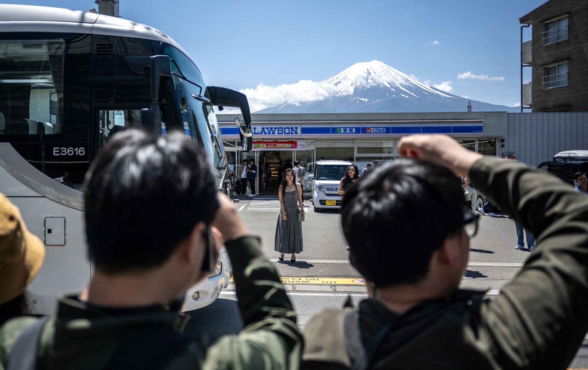 Tourists taking pictures of Mount Fuji from opposite a convenience store on May 3 last year before a huge black barrier was installed to block the view in the town of Fujikawaguchiko, Yamanashi prefecture. Photo: AFP