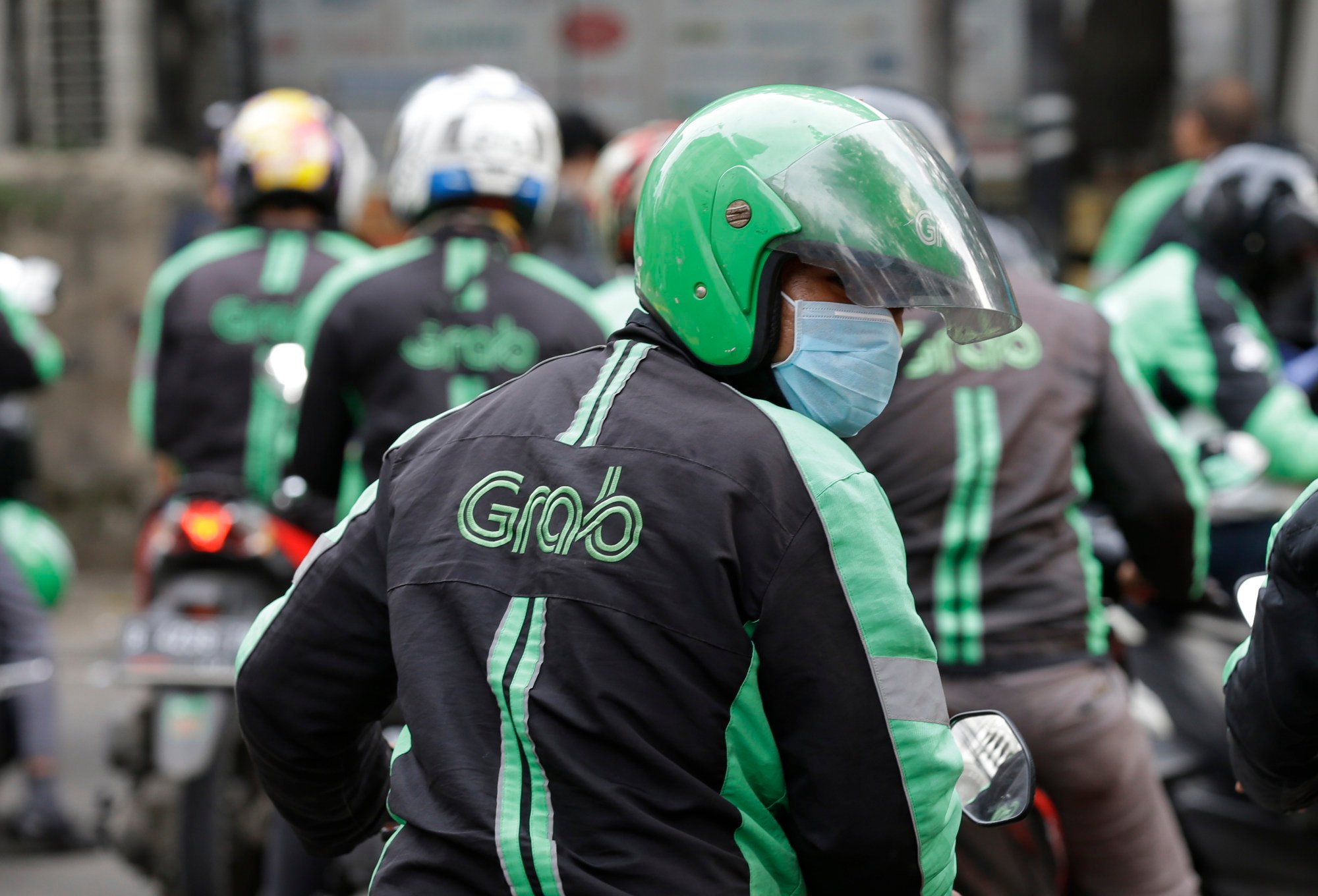 A GrabBike driver rides on his motorbike in Jakarta, Indonesia. Grab Indonesia has dismissed speculation about the merger. Photo: AP A GrabBike driver rides on his motorbike in Jakarta, Indonesia. Grab Indonesia has dismissed speculation about the merger. Photo: AP