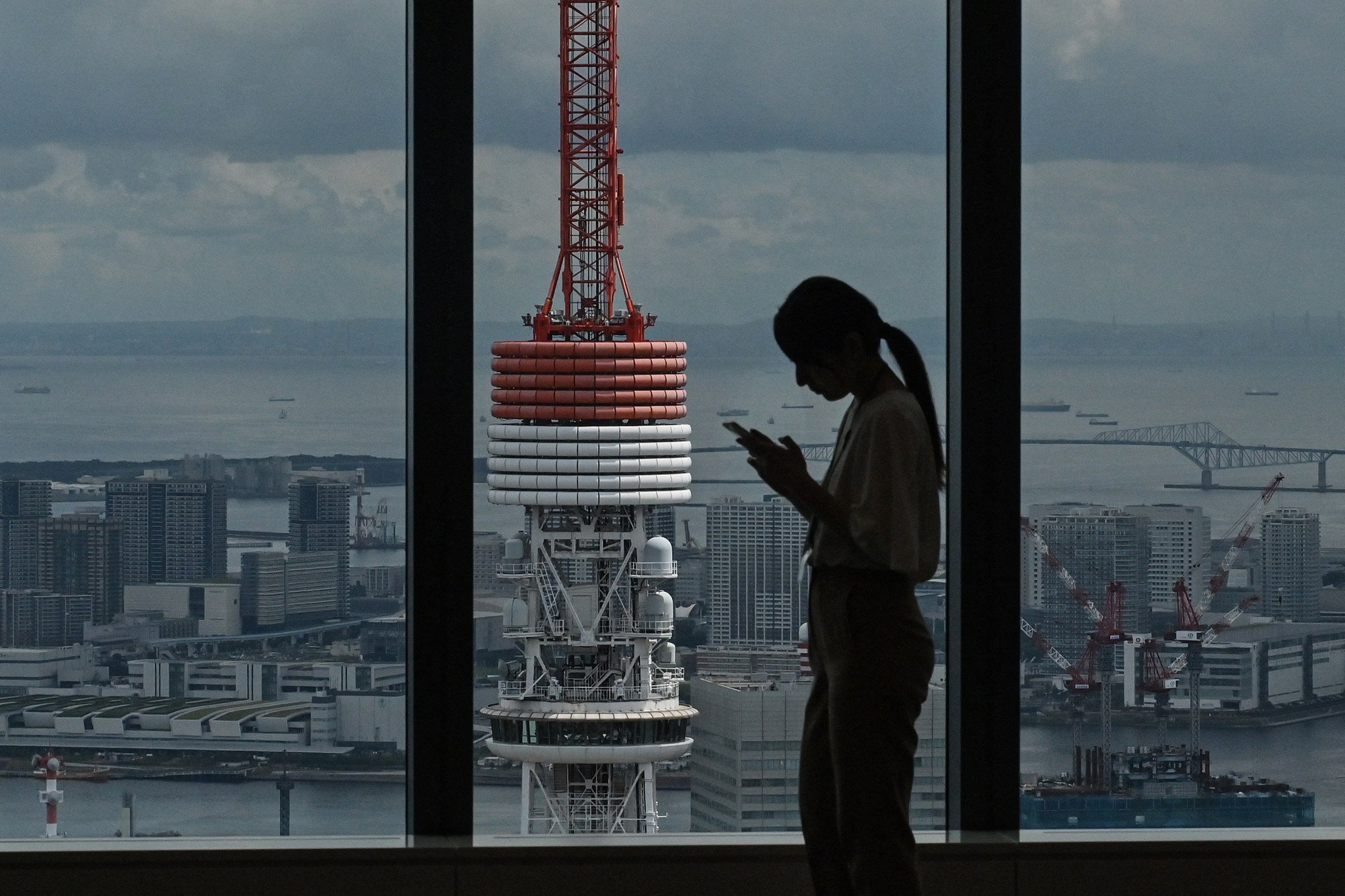 A woman looks at her phone with Tokyo Tower in the background. Photo: AFP A woman looks at her phone with Tokyo Tower in the background. Photo: AFP