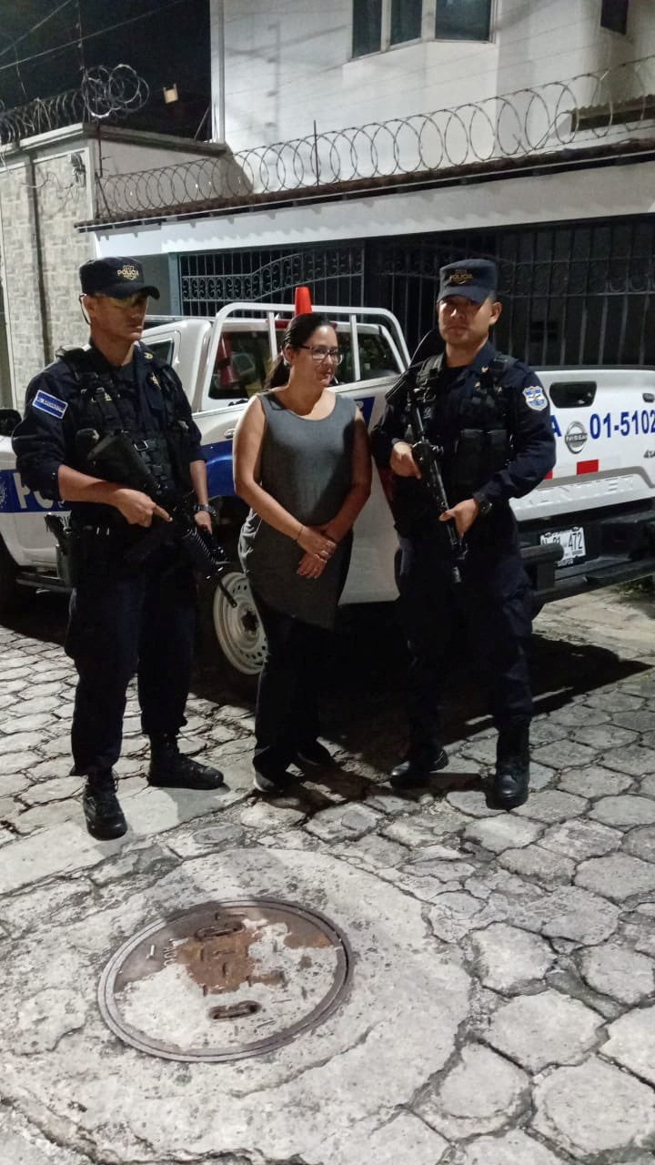 Ruth Eleonora Lopez, anti-corruption and justice director of Cristosal, stands next to El Salvadoran police officers. Photo: Fiscalia General de la Republica El Salvador/Handout via Reuters.