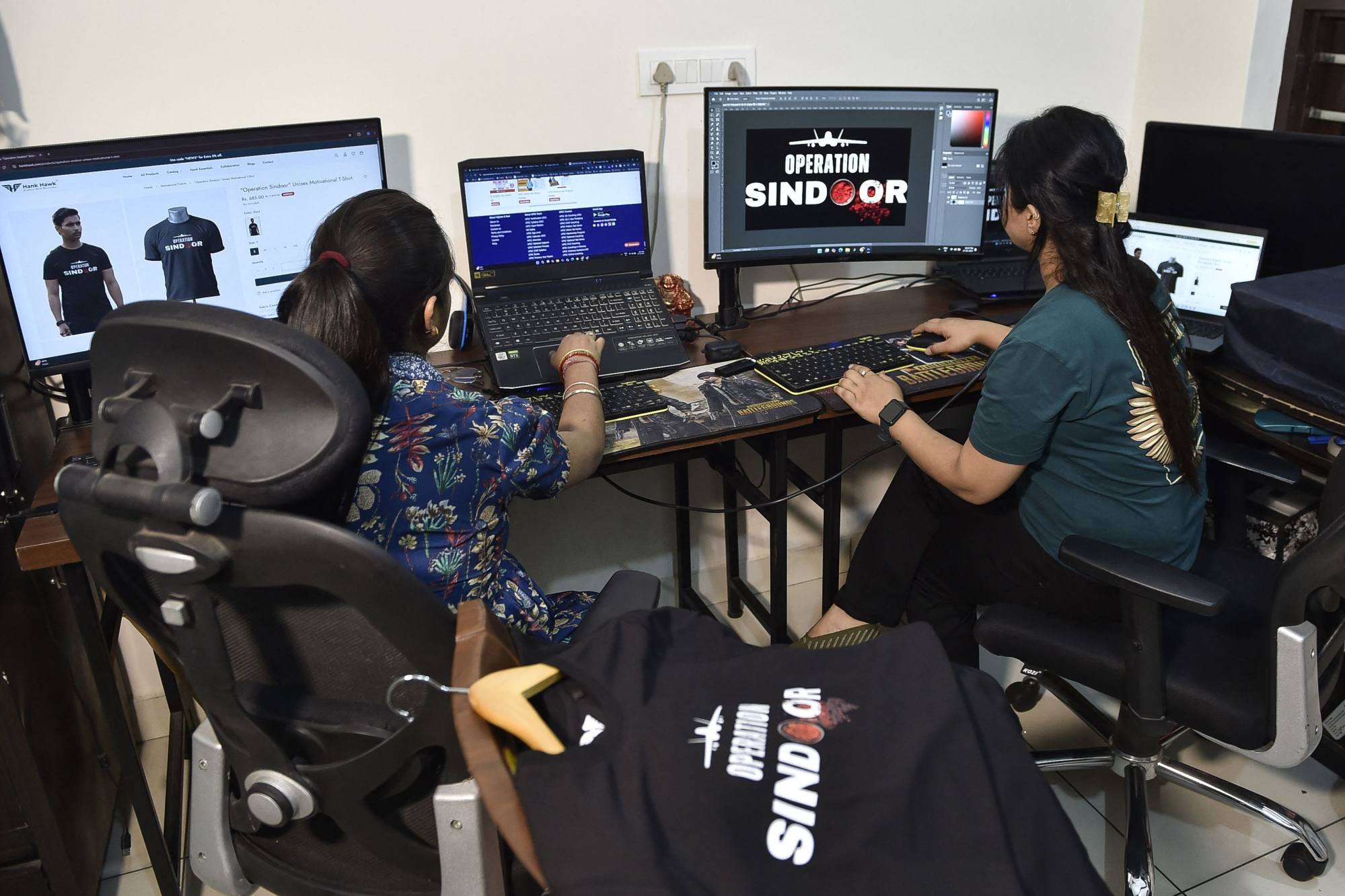 Employees at a store work on designing T-shirts. Photo: AFP Employees at a store work on designing T-shirts. Photo: AFP