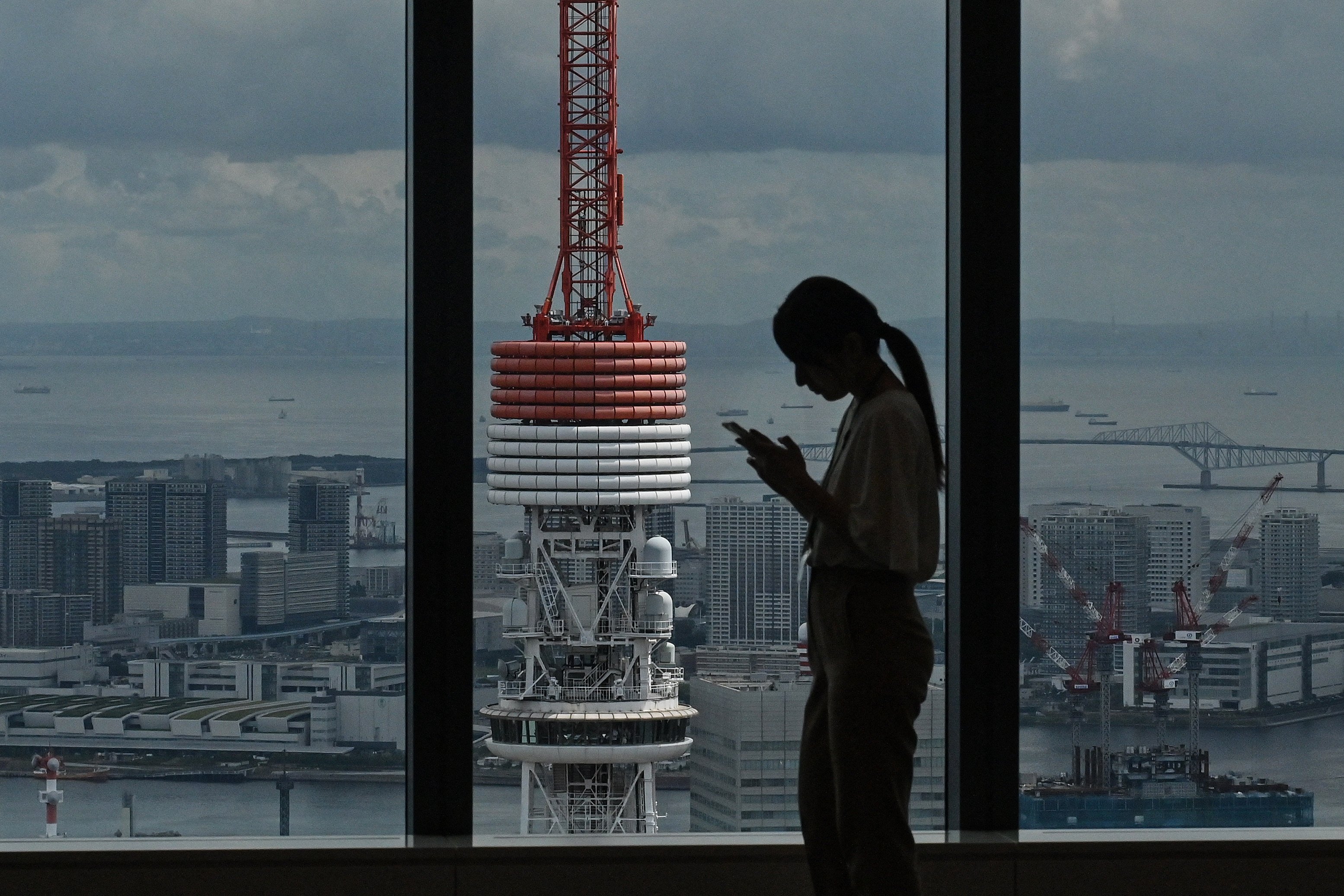 A woman checks her phone near Tokyo Tower in central Tokyo. Japanese police have warned that romance scammers are increasingly using dating apps to target vulnerable individuals. Photo: AFP