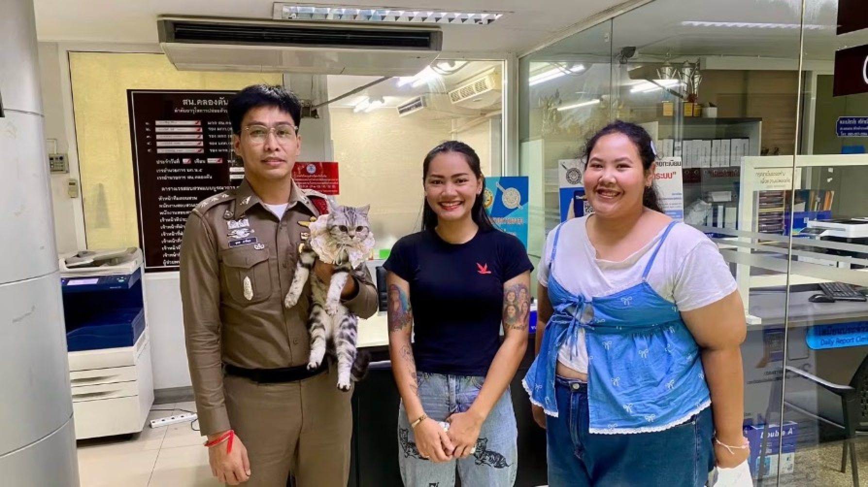 The cat’s owners cheerfully posed for a farewell photo with the kind-hearted police officer who released the feline without any charges. Photo: Parinda Yukol Pakeesuk/Facebook The cat’s owners cheerfully posed for a farewell photo with the kind-hearted police officer who released the feline without any charges. Photo: Parinda Yukol Pakeesuk/Facebook