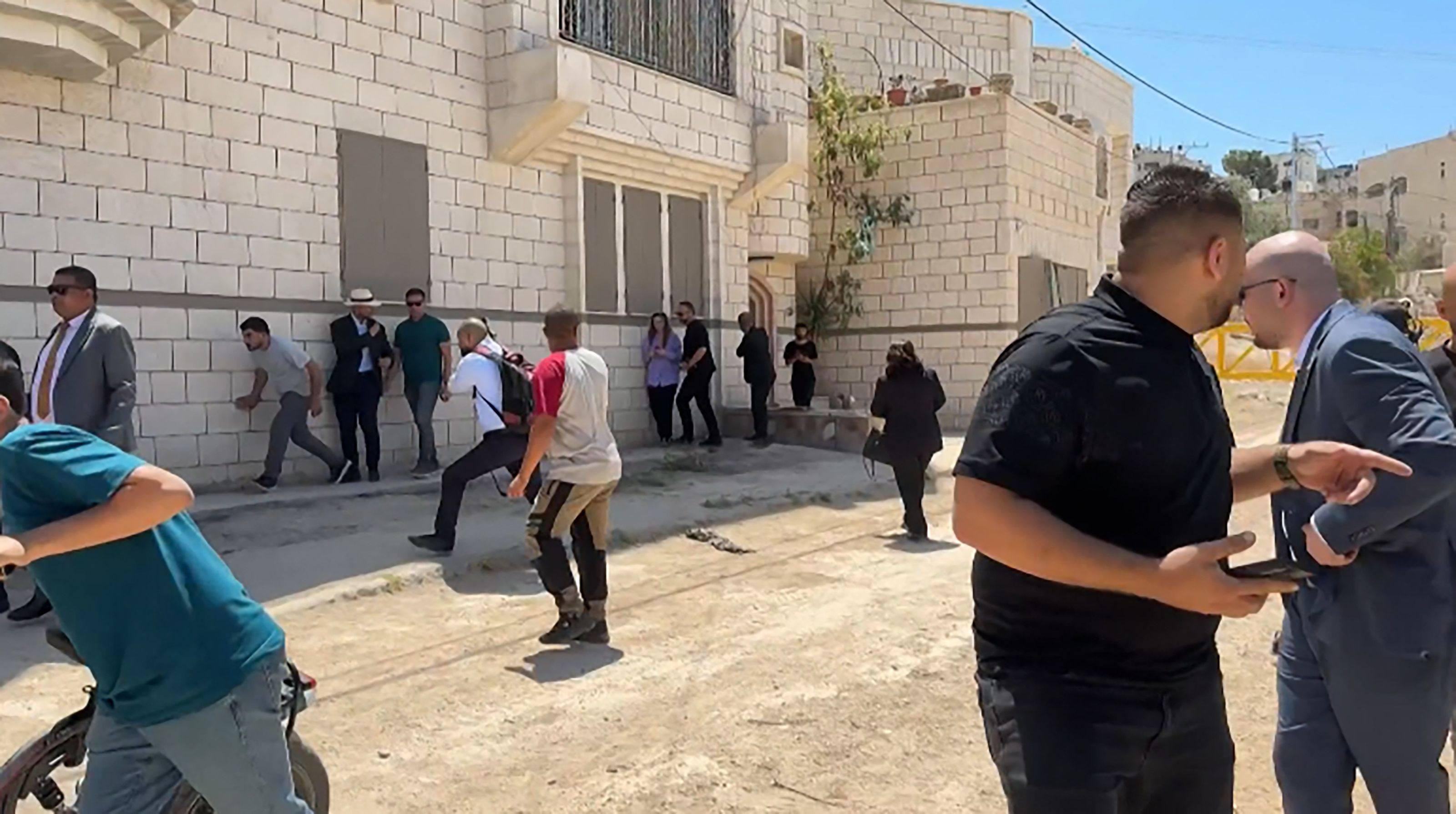 Members of a diplomatic delegation react after warning shots were fired in the distance. Photo: AFP