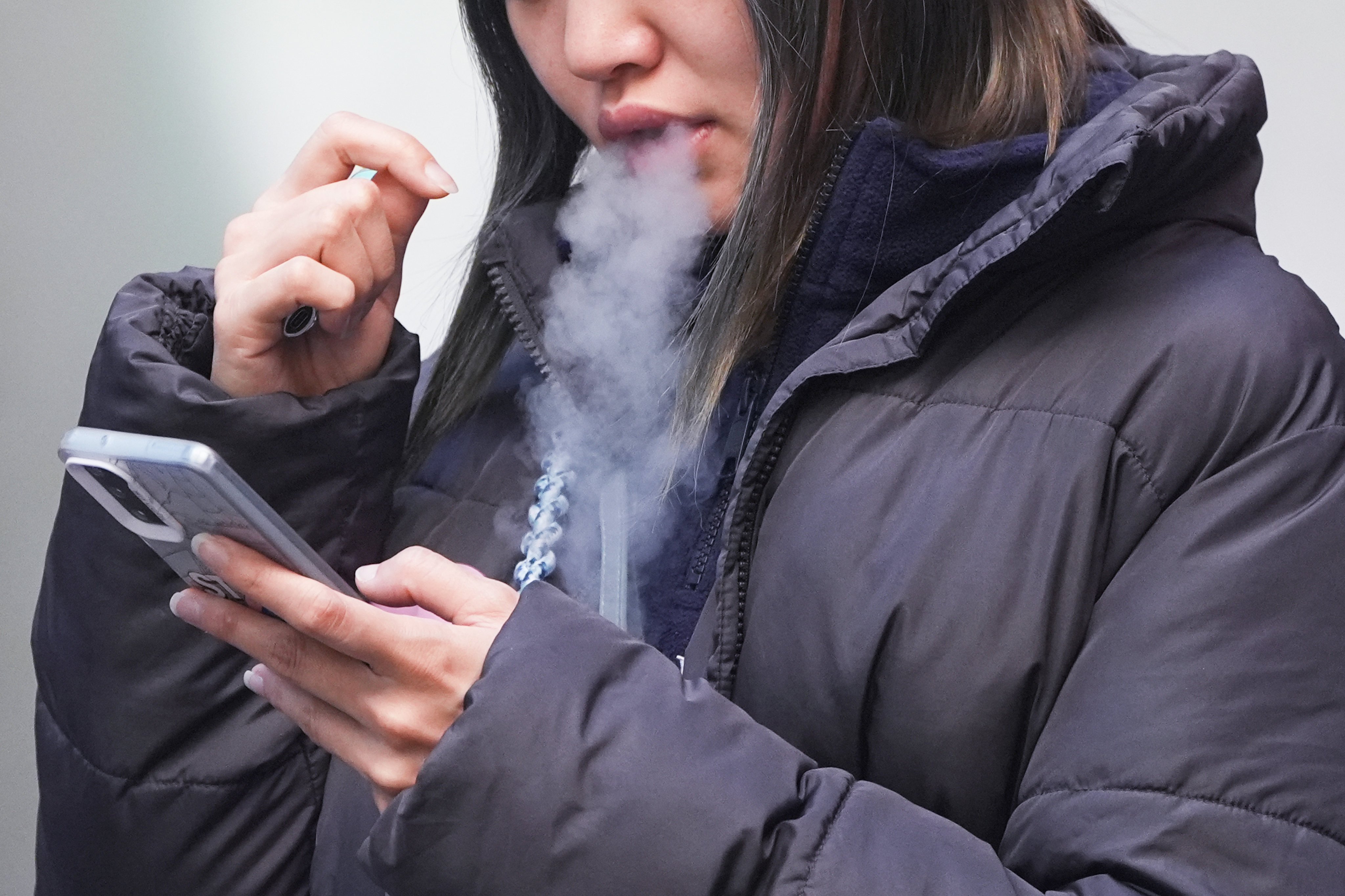 A woman smokes an e-cigarette in Mong Kok. More than one-third of regular smokers polled said they supported plain packaging, according to one university poll. Photo: Eugene Lee