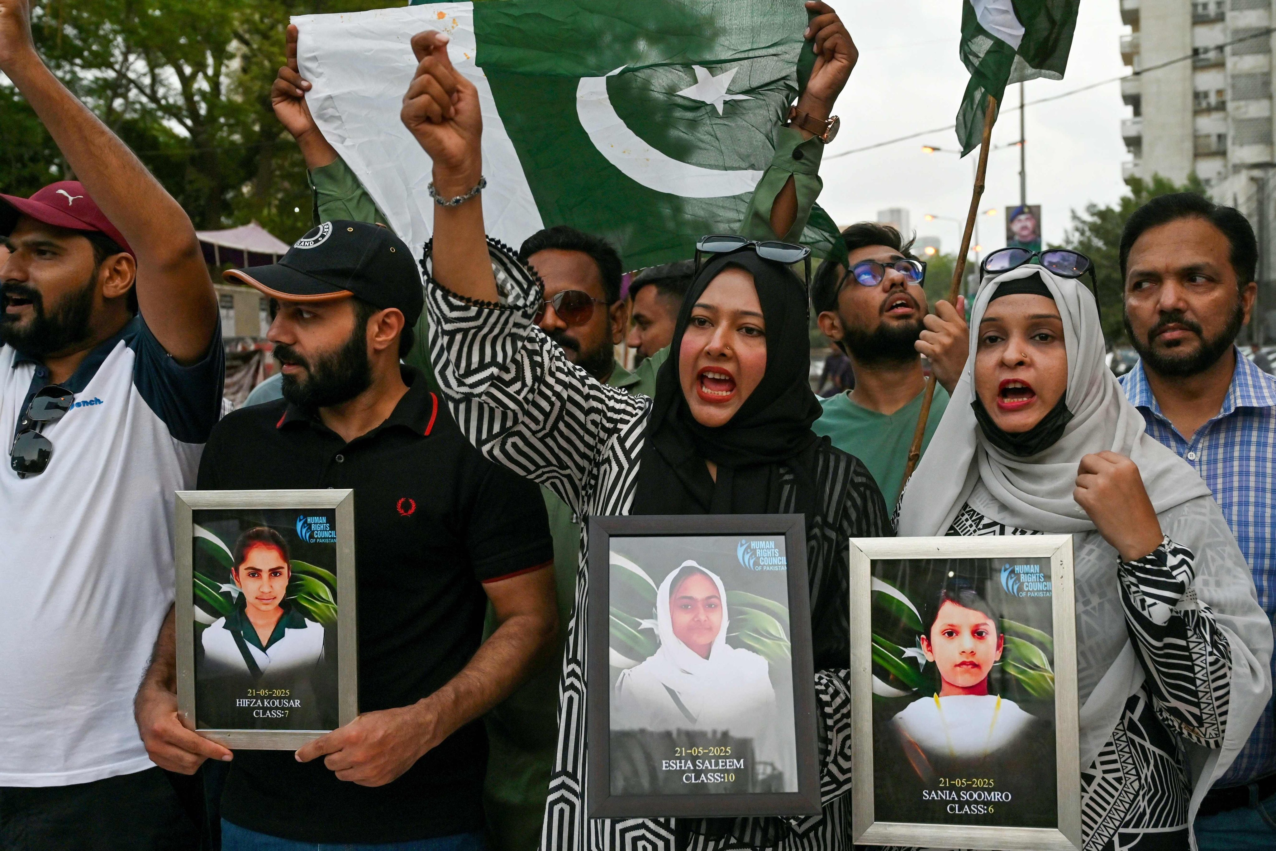 Human rights activist hold portraits of children killed in the school bus bombing in Balochistan, during a rally in Karachi on Wednesday. Photo: AFP