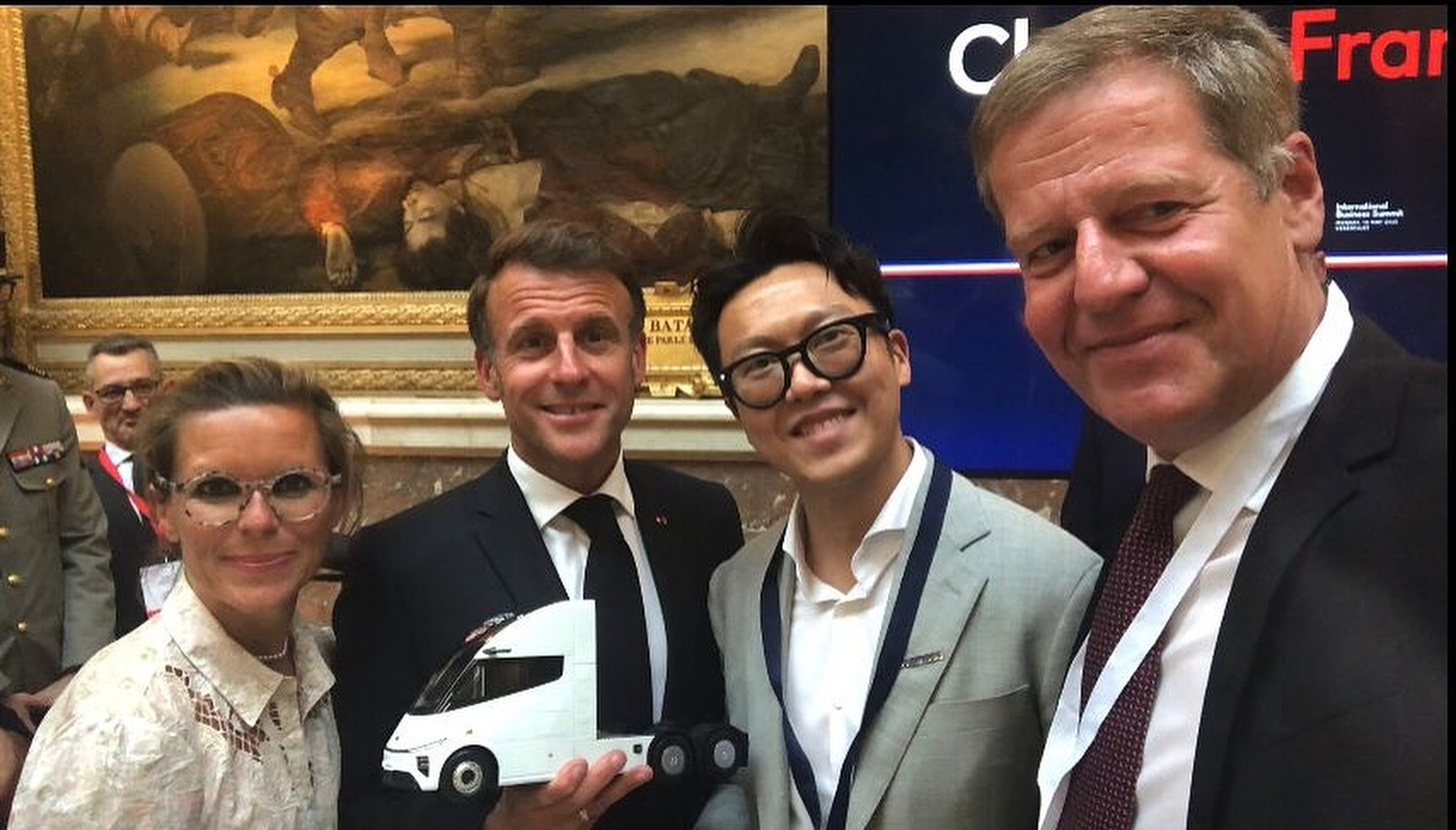 French President Emmanuel Macron (centre) holds a model of an electric lorry made by Windrose, a Chinese company founded by entrepreneur Wen Han (right), at the Choose France summit in Versailles, France on Monday. Photo: Instagram/whan6023