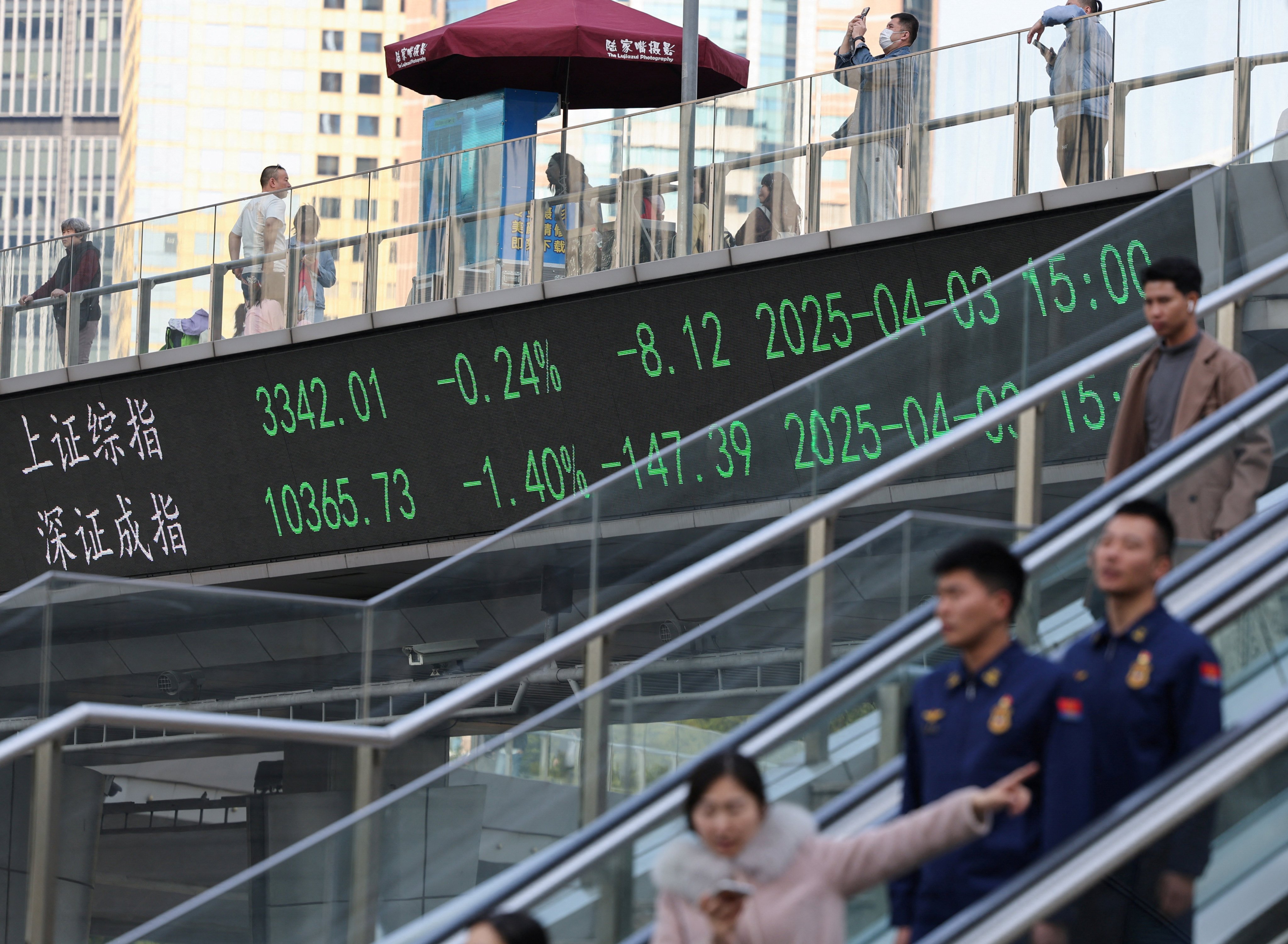 An electronic board shows Shanghai and Shenzhen stock indices as people cross a pedestrian bridge in Shanghai on April 3. China’s top internet watchdog is targeting social media accounts that spread false information about the capital markets. Photo: Reuters