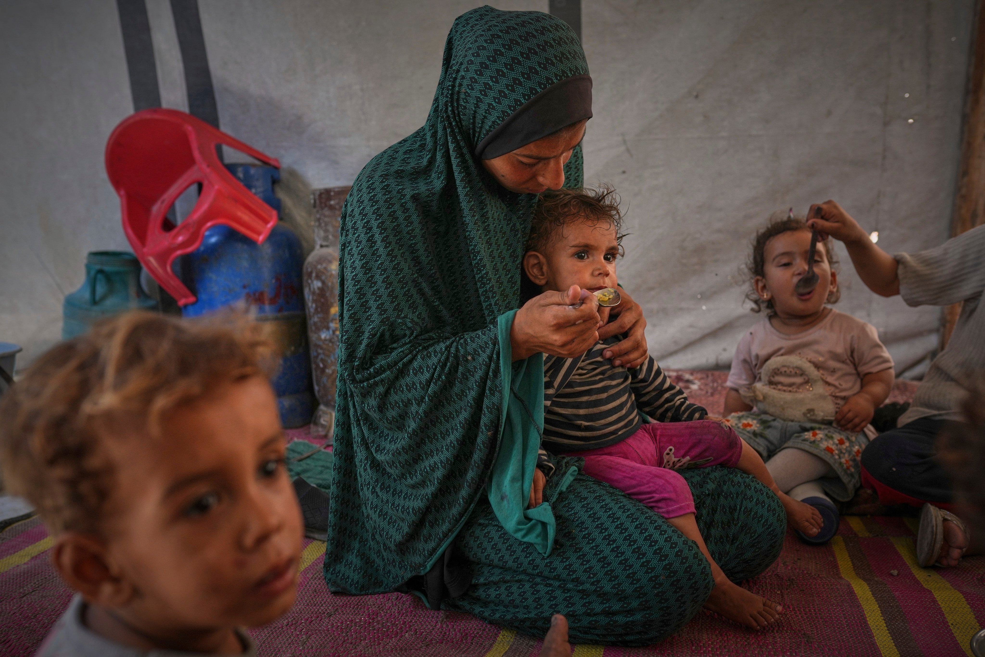 A Palestinian woman feeds her children at a tent sheltering a displaced family in central Gaza City on May 24. Photo: AP