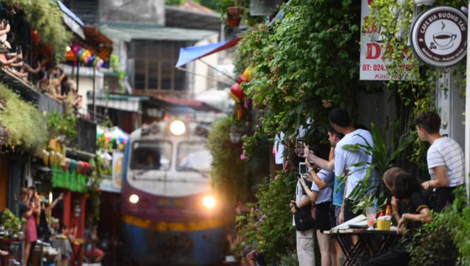 Tourists take photos of a train passing through an old residential area in central Hanoi. Photo: AFP/Nhac Nguyen