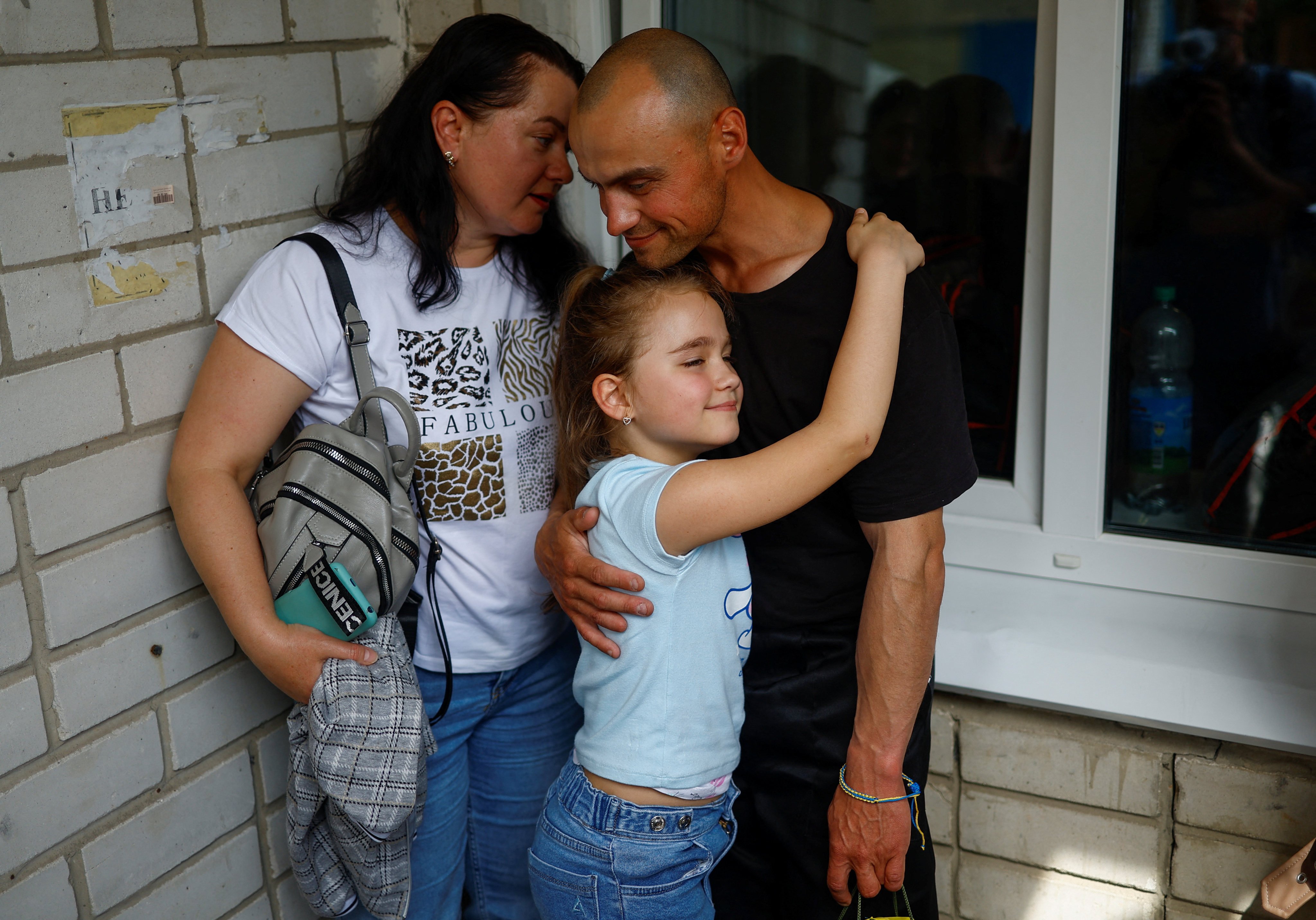 Ukrainian prisoner of war Viktor embraces his daughter Milana and wife Iryna as he returns after a prisoner swap in an undisclosed location in Ukraine on Sunday. Photo: Reuters