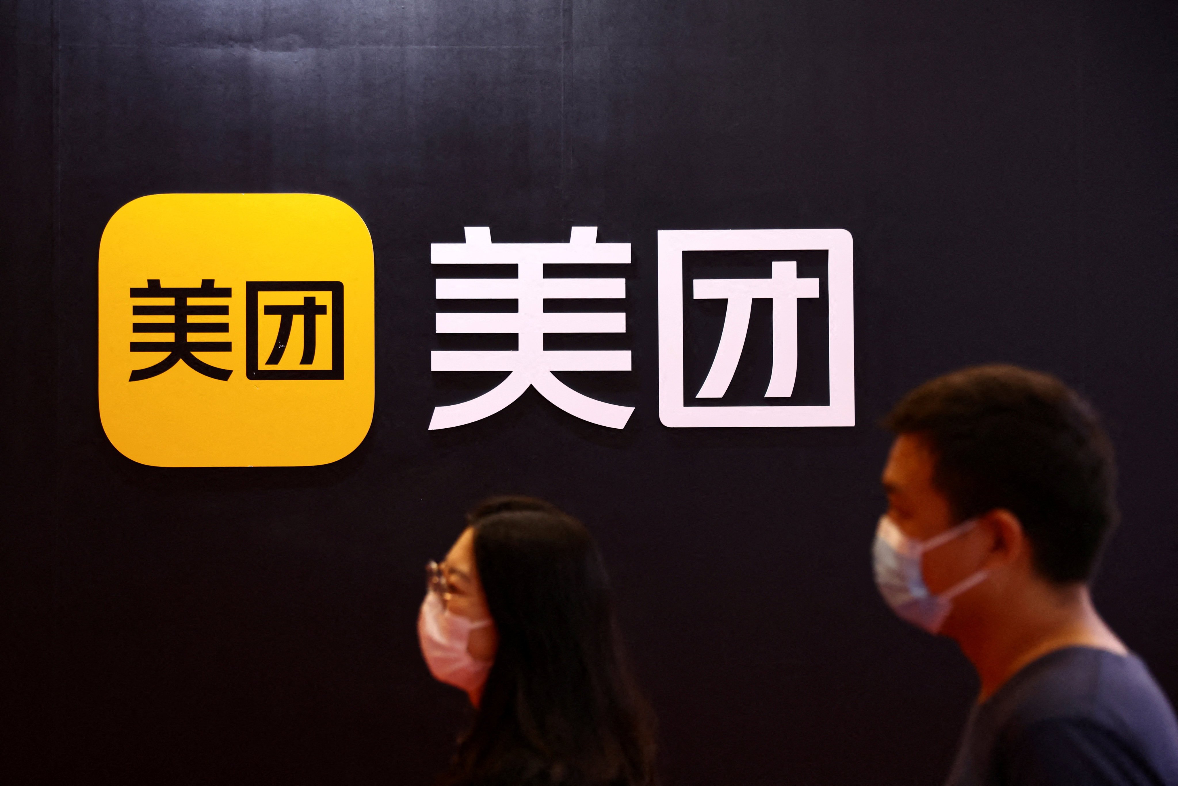 People walk past a logo of Meituan at its booth at the 2022 World Robot Conference in Beijing on August 18, 2022. Photo: Reuters