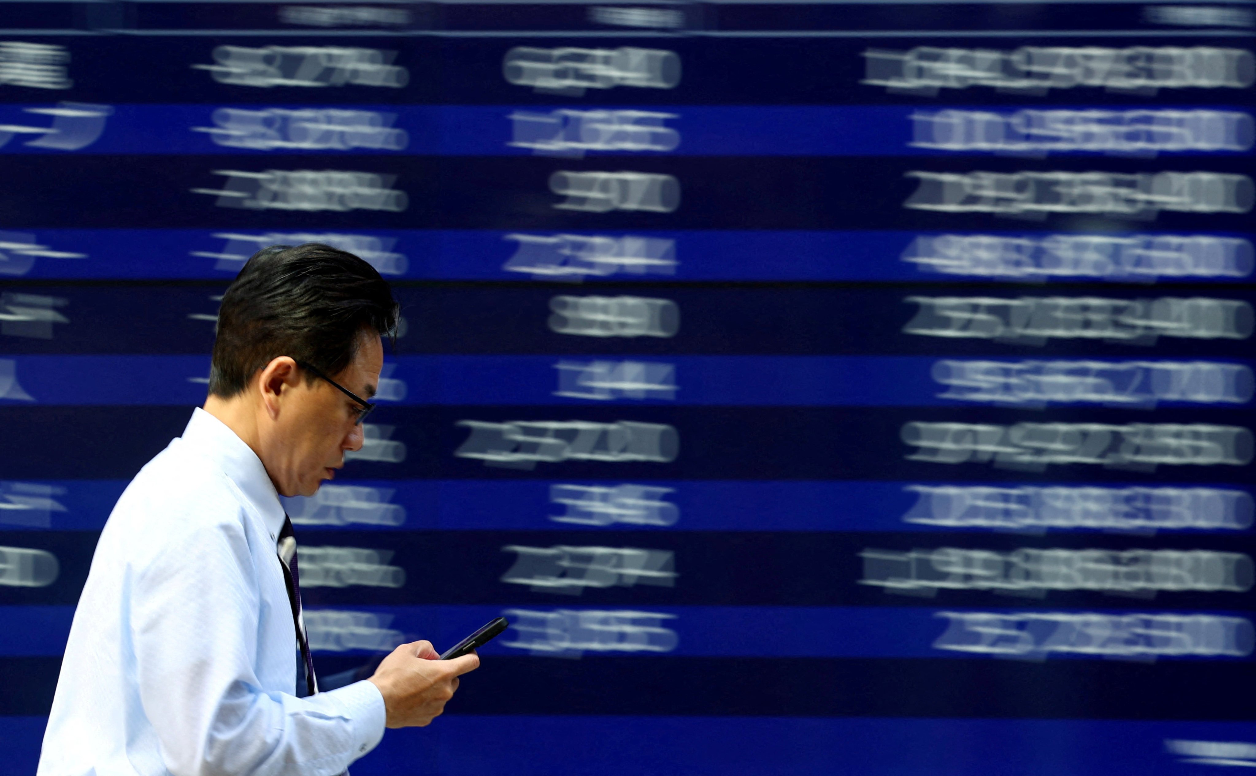 A man walks past an electronic screen displaying stock quotations in Tokyo on April 15. Photo: Reuters