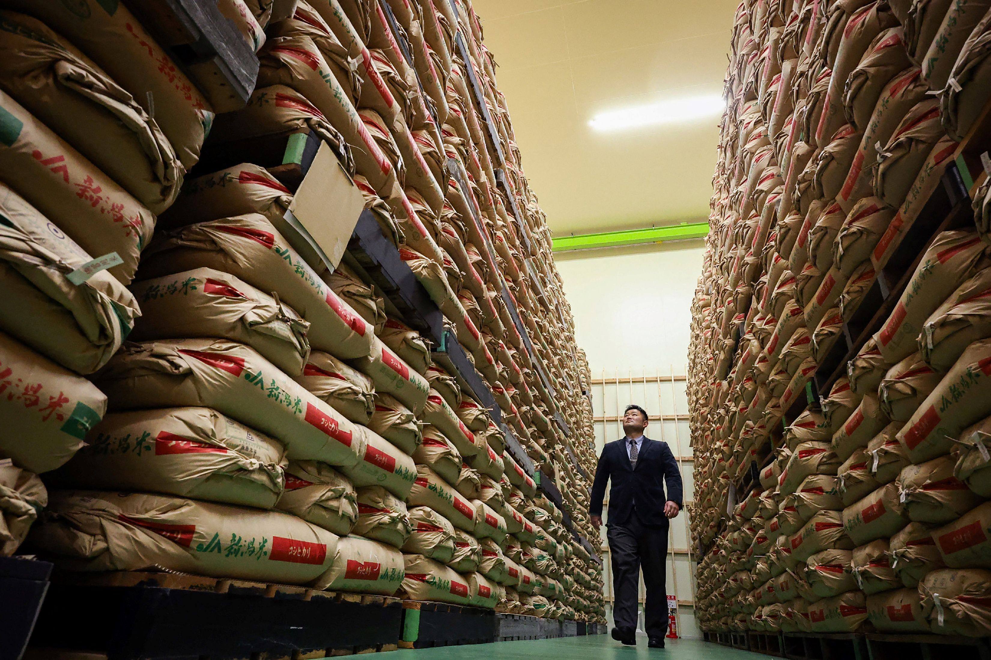 A man walks past sacks of government-stockpiled rice stored at a warehouse in Japan’s Saitama prefecture. Photo: JIJI Press/AFP