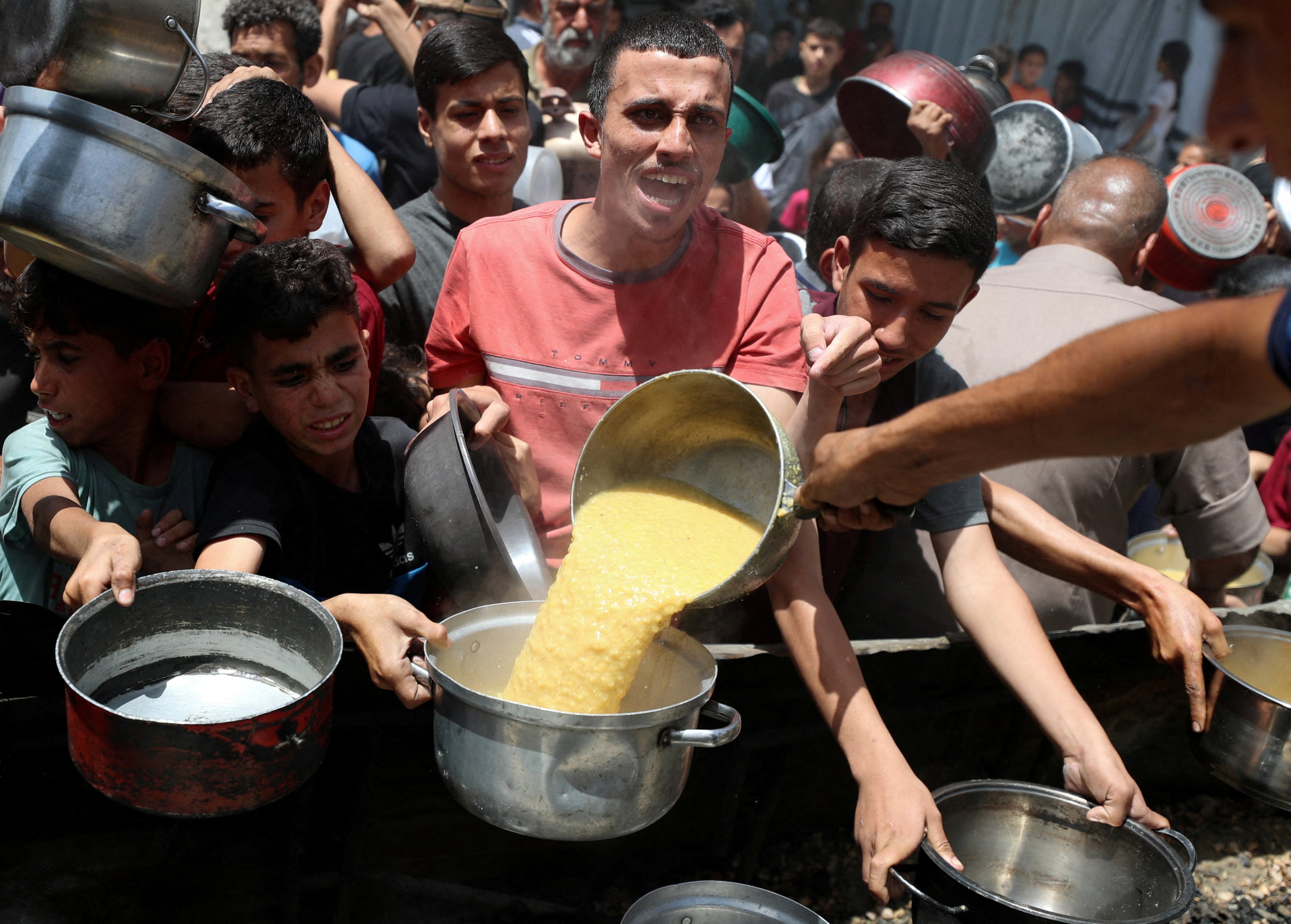 Hungry Palestinians wait to receive food cooked by a charity kitchen in Jabalia, the northern Gaza Strip, on May 19. Photo: Reuters