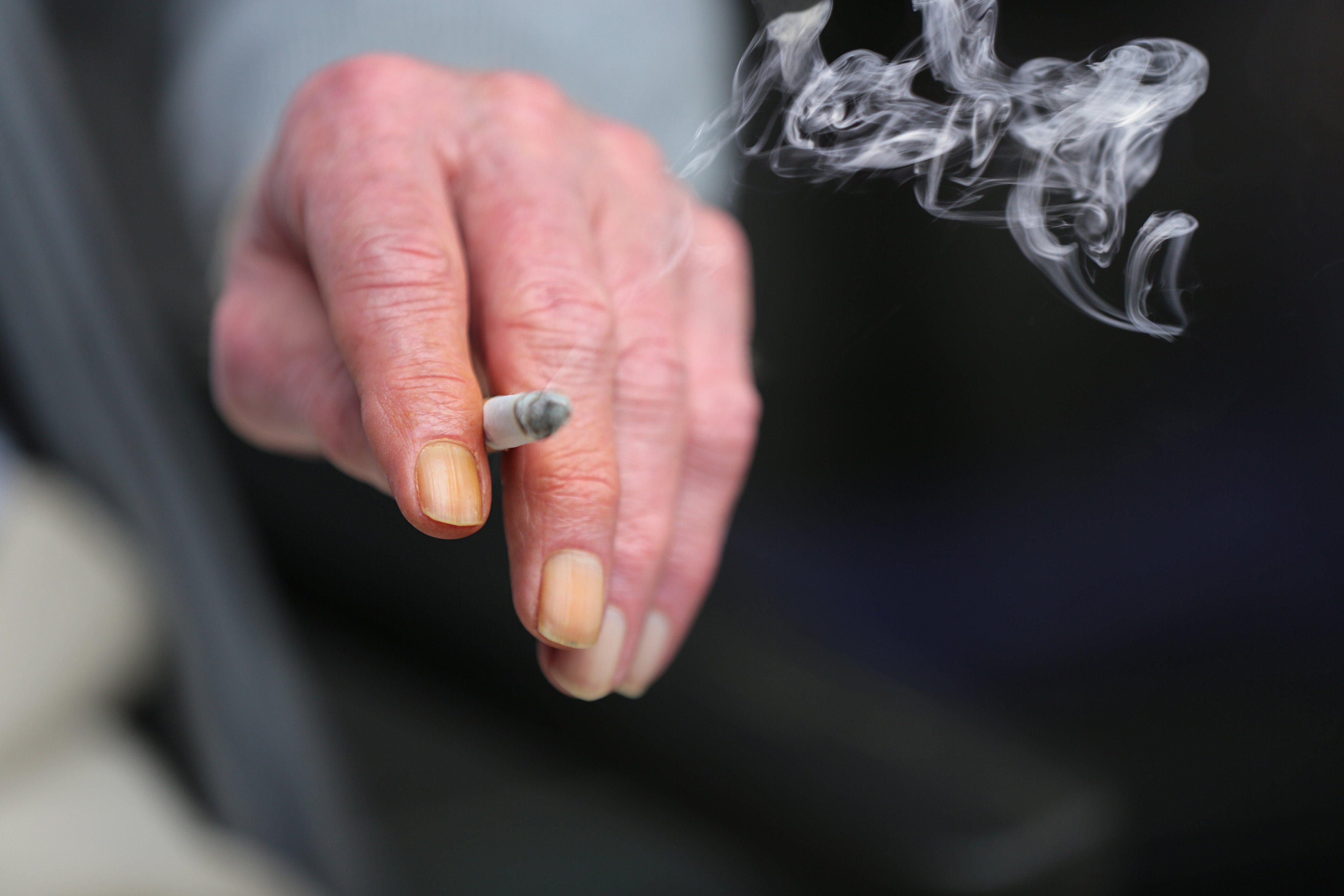 A smoker with stained fingernails holds a cigarette. Photo: Shutterstock