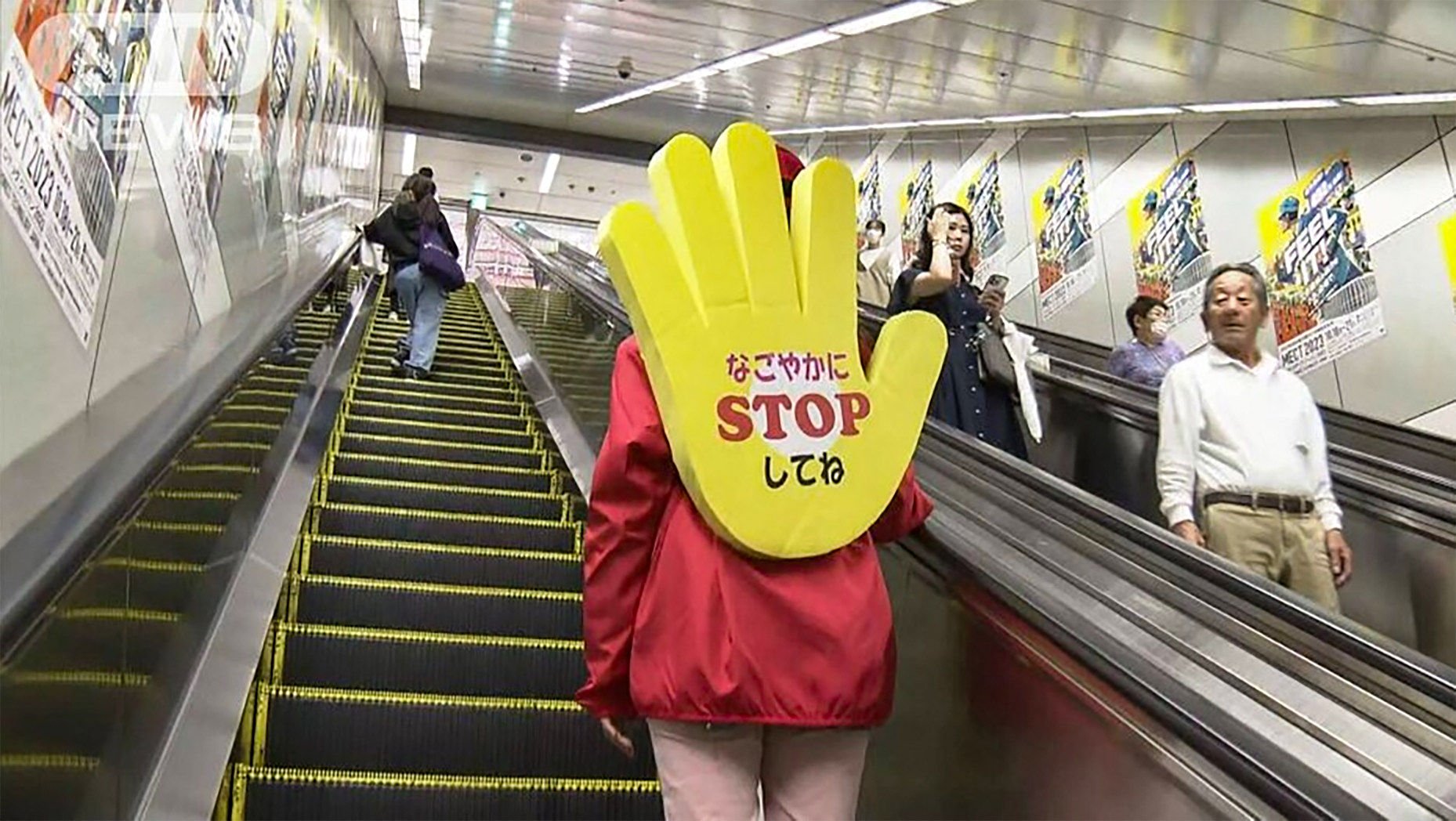 A member of the “Stop and Stand Squad” in Japan’s Nagoya city wears a huge yellow hand as a backpack, emblazoned with a phrase that translates as “Please stop tranquilly”, to stop people from walking up escalators. Photo: ANN News
