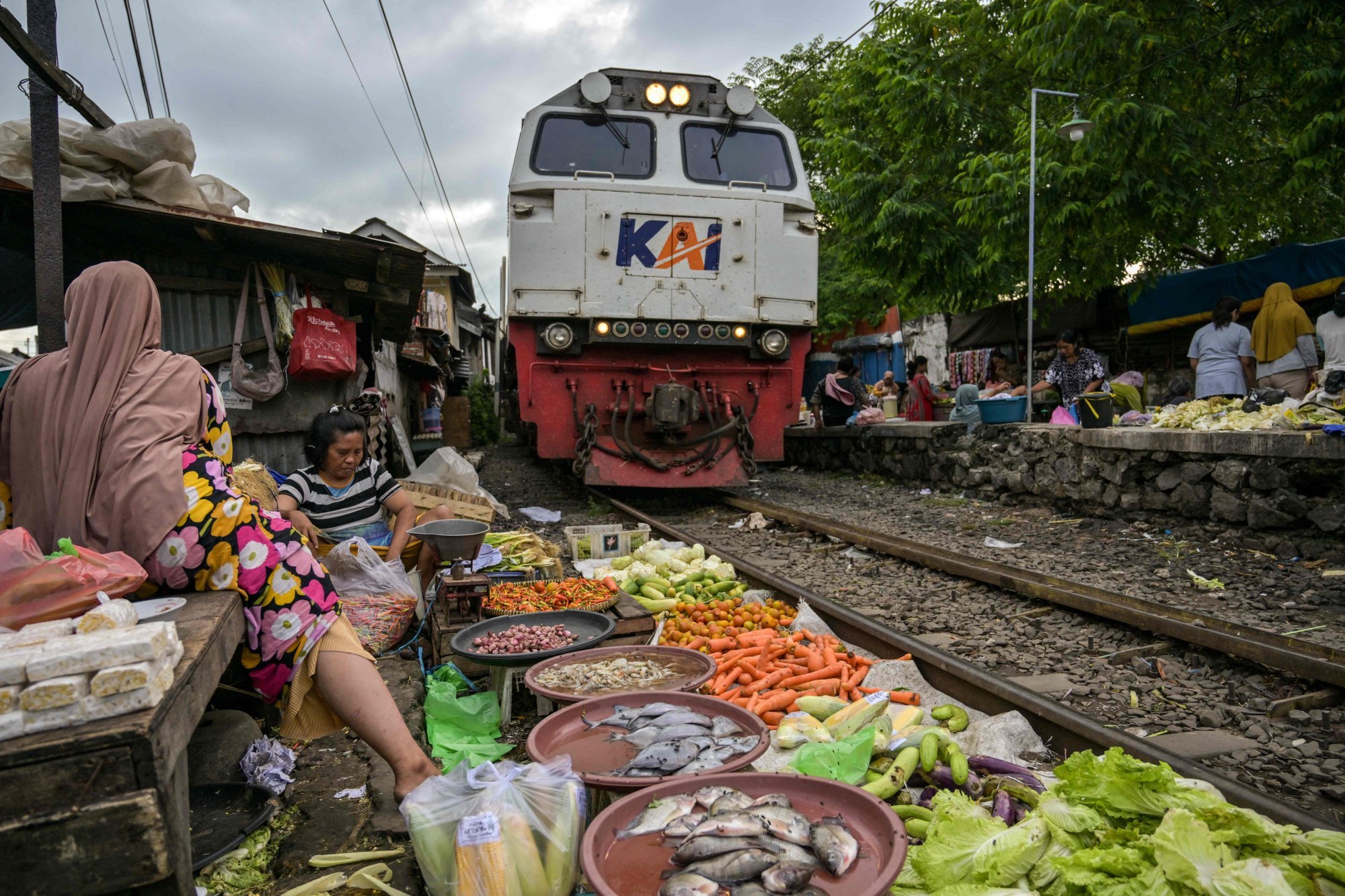 A train slowly makes its way past vendors selling products at a market along a railway line in Surabaya on May 25. Photo: AFP A train slowly makes its way past vendors selling products at a market along a railway line in Surabaya on May 25. Photo: AFP