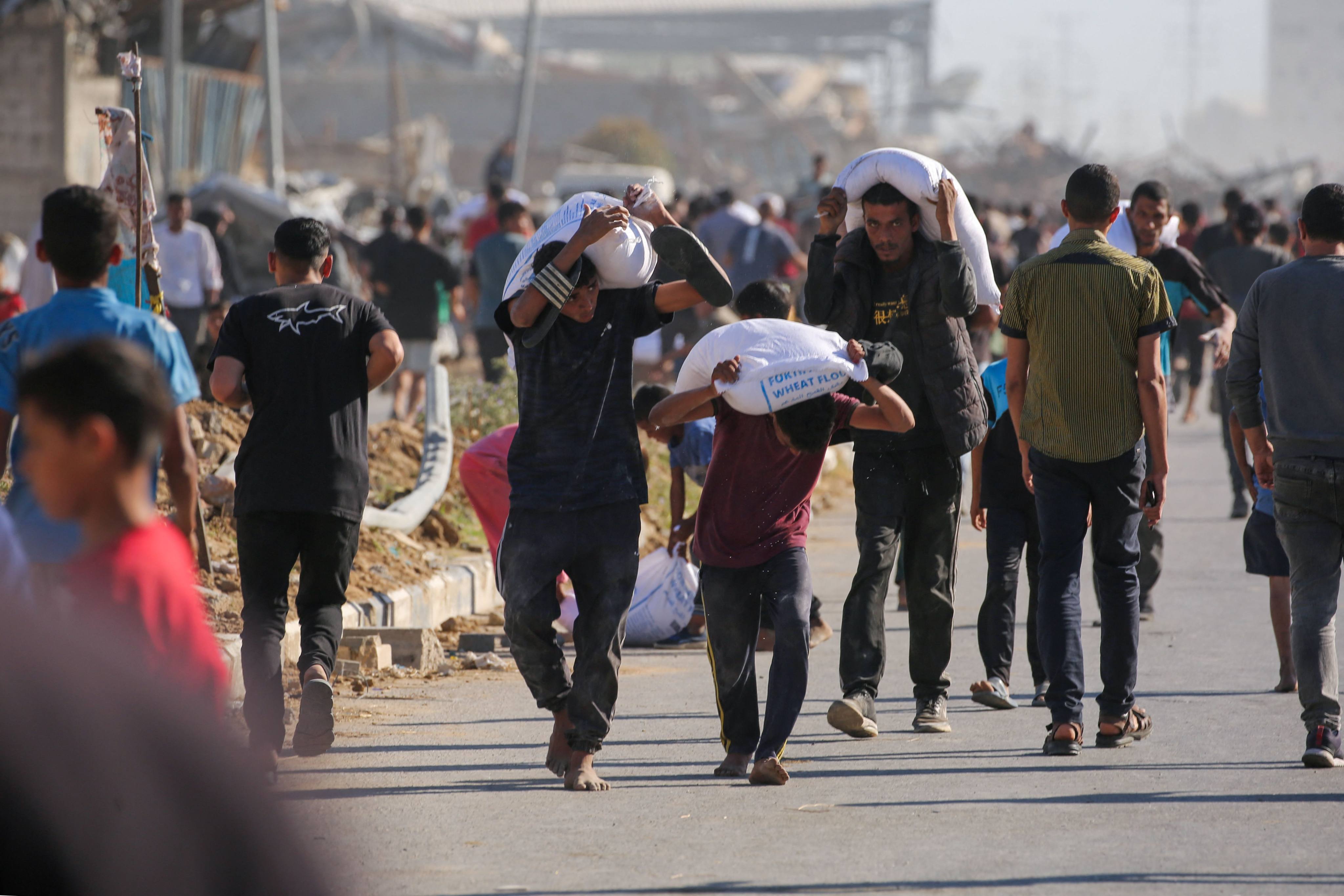 Displaced Palestinians ferry bags of food aid after people stormed a World Food Programme warehouse in Deir el-Balah in the central Gaza Strip on Wednesday. Photo: AFP