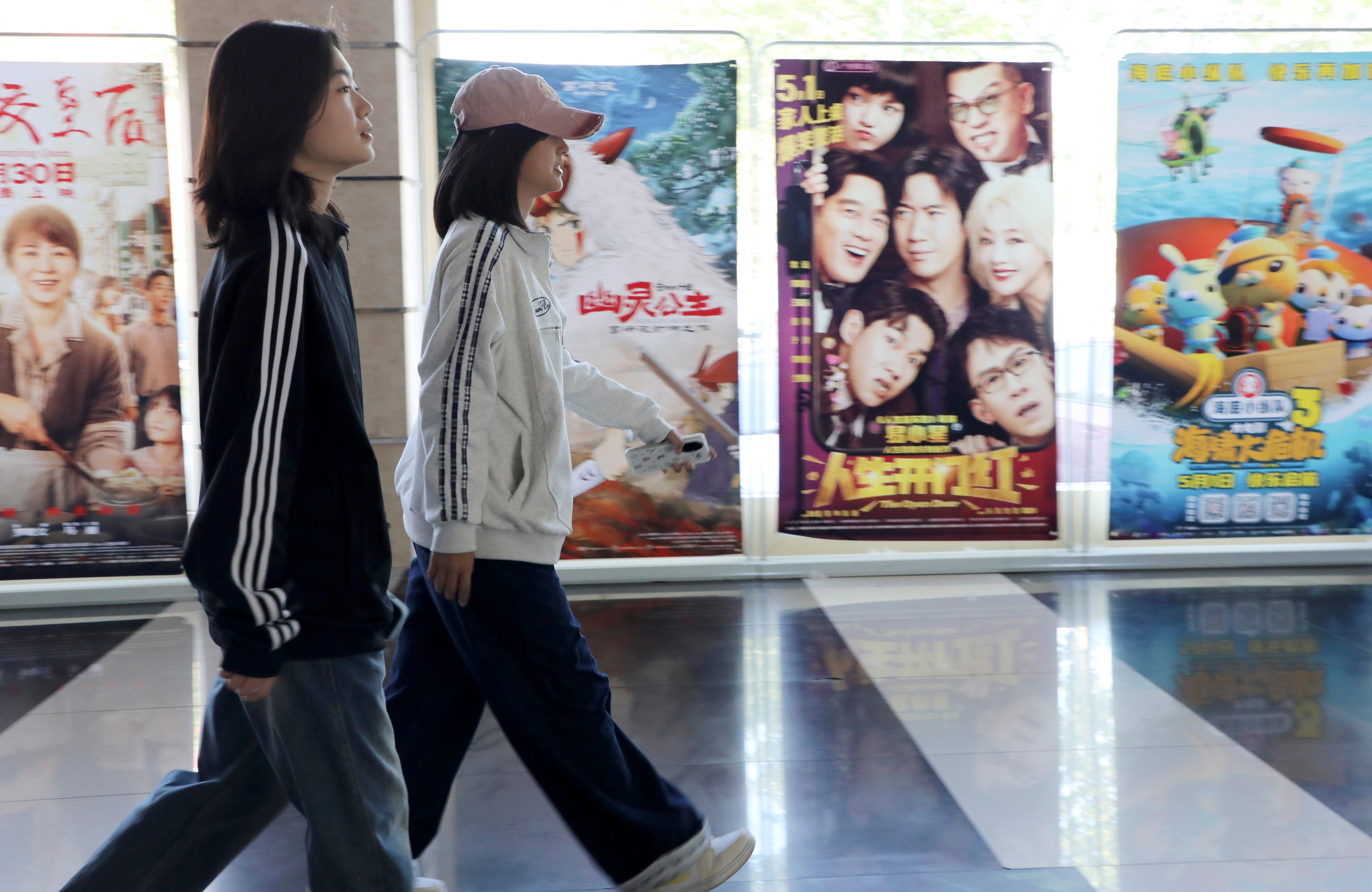 (250504) -- BINZHOU, May 4, 2025 (Xinhua) -- People walk past movie posters at a cinema in Boxing County of Binzhou City, east China’s Shandong Province, May 3, 2025. People across China enjoy the ongoing May Day holiday in various ways. (Photo by Chen Bin/Xinhua)