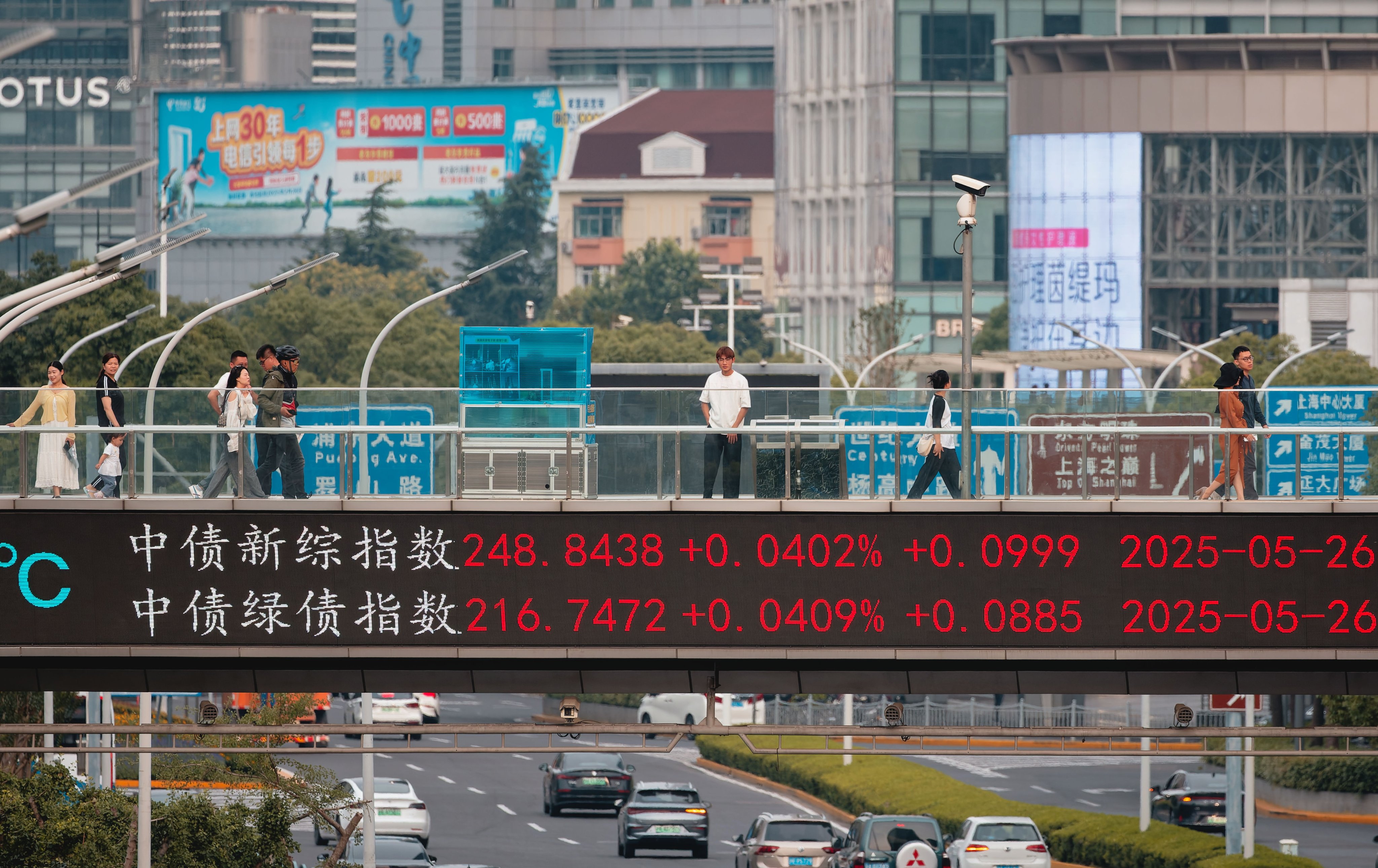 People walk across a pedestrian bridge showing stocks and indices in Shanghai. Photo: EPA-EFE