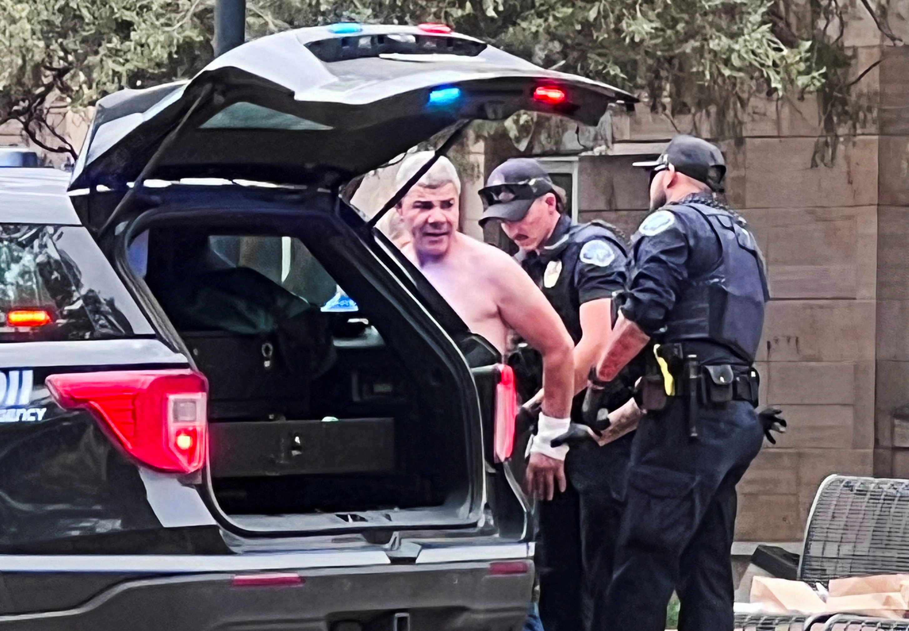 Law enforcement officers detain a shirtless suspect. Photo: X/@OpusObscuraX via Reuters