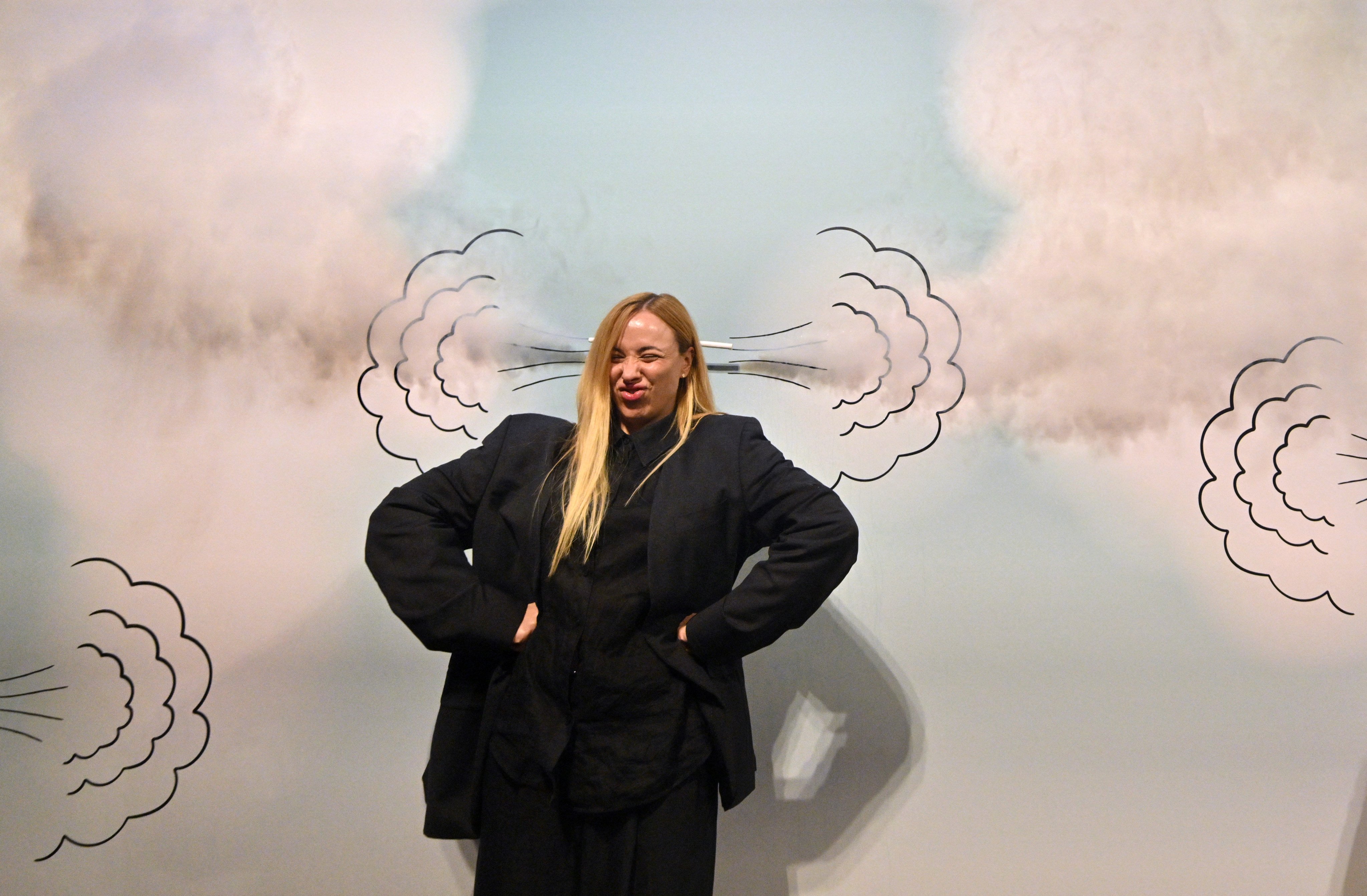A visitor poses for a picture in front of a drawing on a wall during a visit to the “Third Wind” interactive exhibition in Kyiv, Ukraine, on April 27, 2025. The exhibition aims to help visitors understand their emotions, relieve stress and find their inner child amid the Russian invasion of Ukraine. Photo: AFP