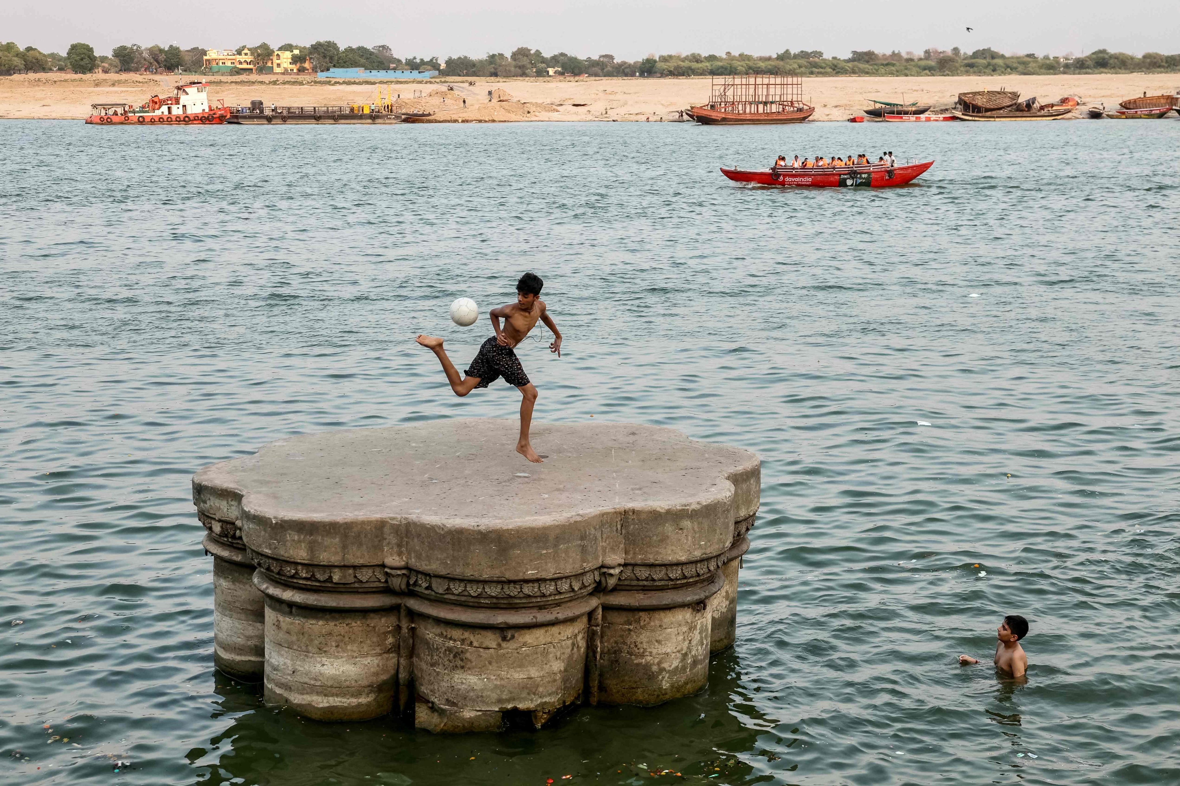 A boy kicks a football along the banks of the river Ganges on a hot summer day in Varanasi, India. Photo: AFP