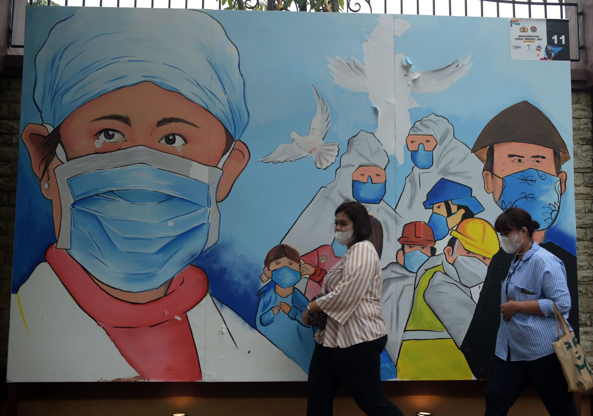 People walk past a mural depicting health workers fighting against Covid-19 in Jakarta, Indonesia, in December 2021. Photo: Xinhua People walk past a mural depicting health workers fighting against Covid-19 in Jakarta, Indonesia, in December 2021. Photo: Xinhua