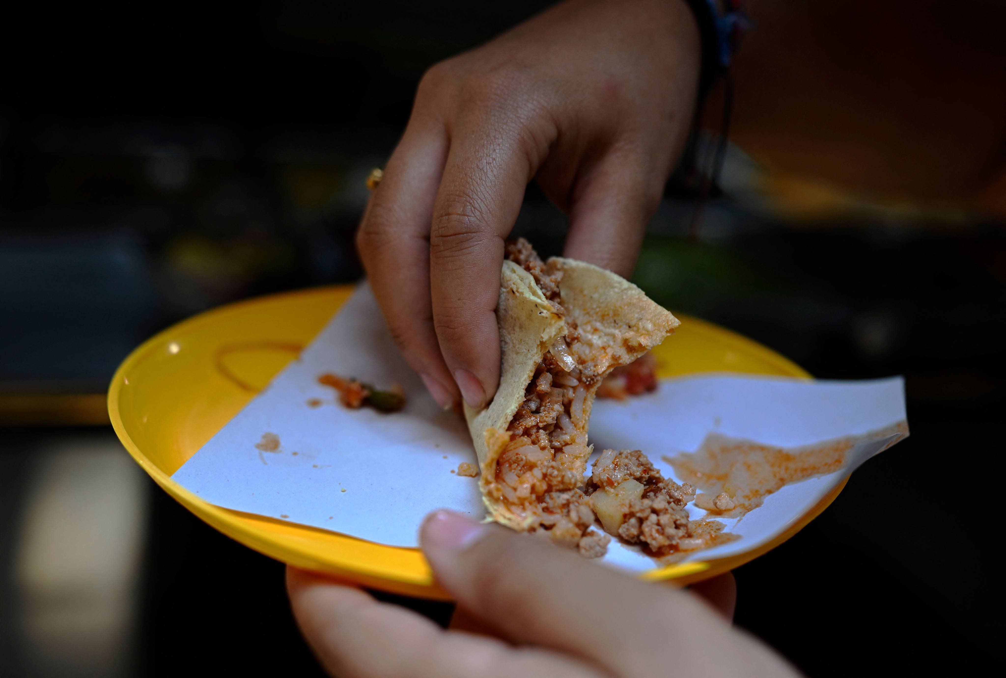 A woman eats a taco at a street food stall in the Roma neighbourhood in Mexico City in May 8. The latest acronym popular among traders and investors is Taco, short for “Trump always chickens out”, a reference to US President Donald Trump’s habit of making concessions after initially talking tough on trade and tariffs. Photo: AFP
