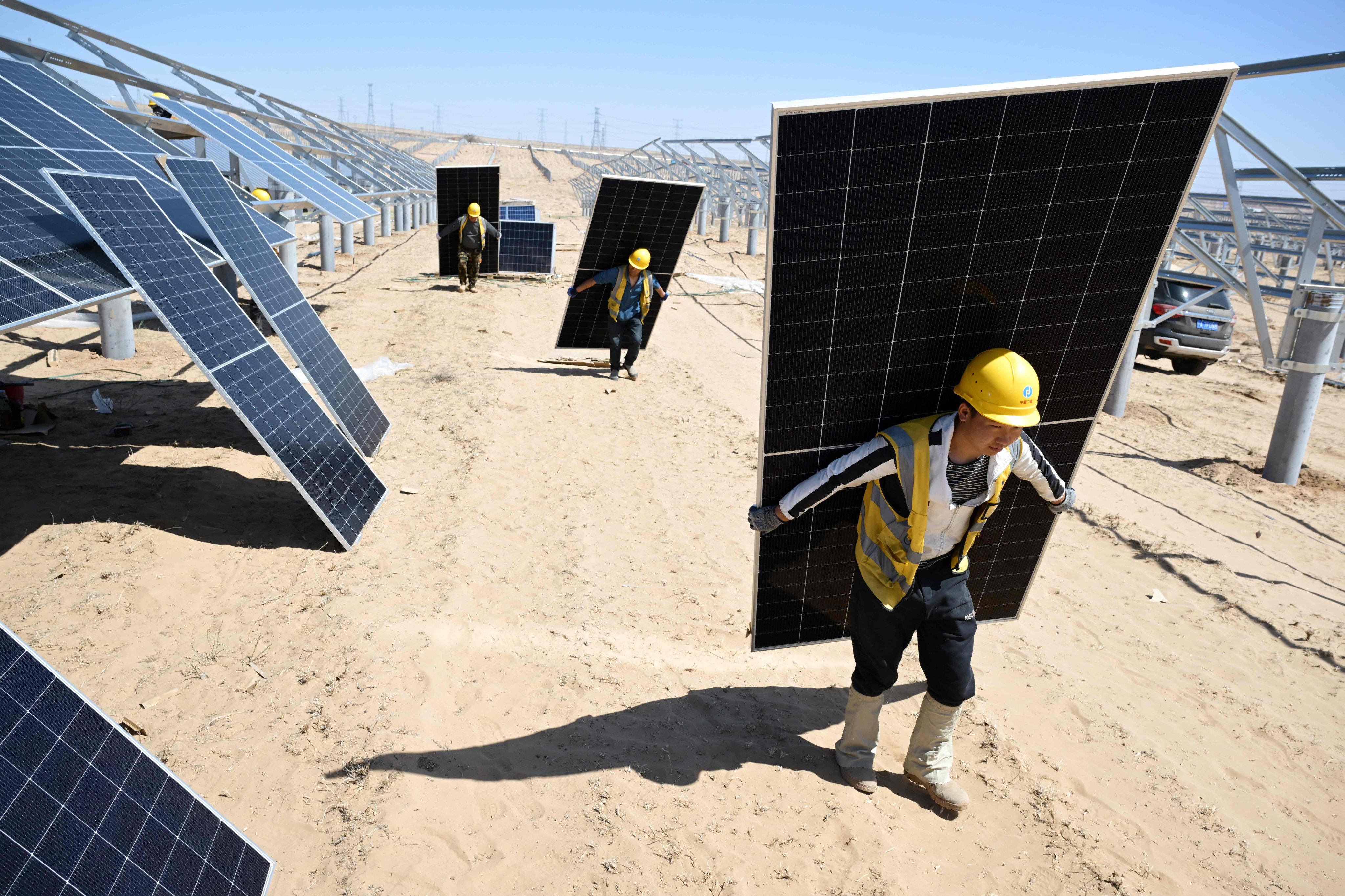 Workers carry solar panels to be installed in the desert at the Ningguoyun Lingwu 1 million kilowatt photovoltaic project in Lingwu, in China’s northern Ningxia Hui autonomous region, on April 14, 2025. Photo: AFP