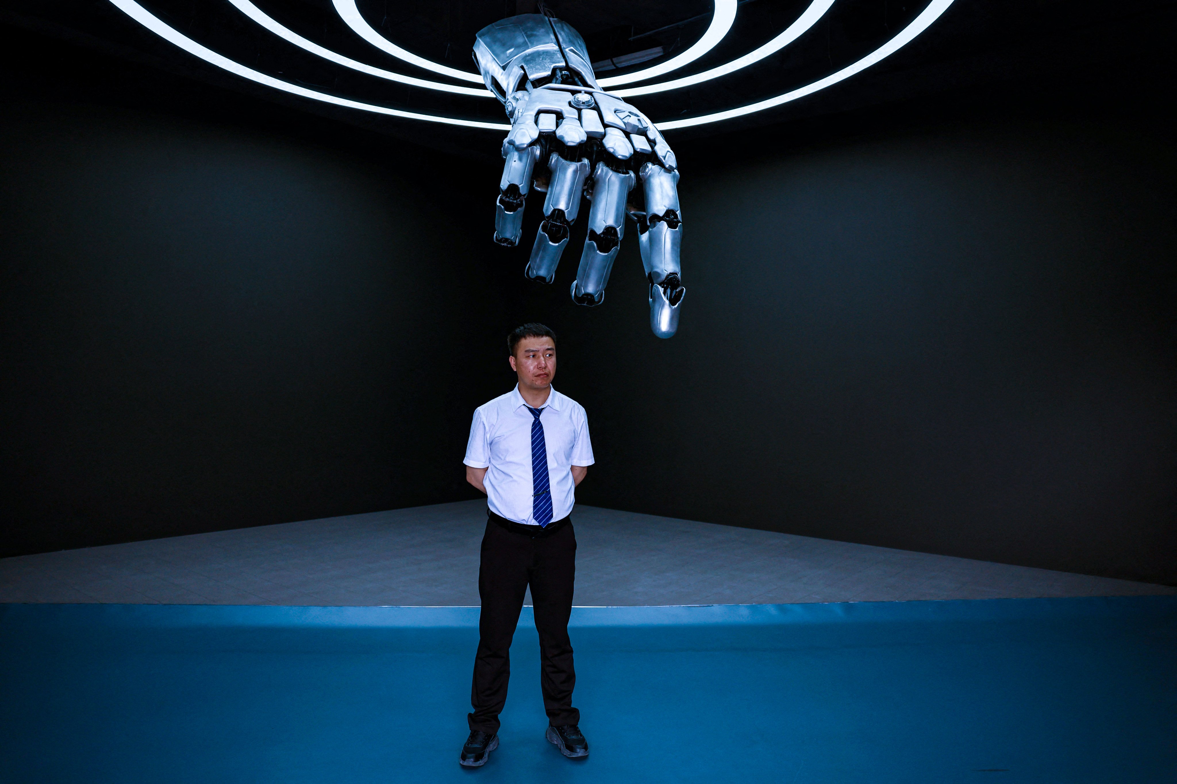 A staff member stands under a robotic hand at an exhibition centre at Beijing Robotics Industrial Park last month. According to a Harvard report, China largely trails the US in all key technology fields, but it is steadily narrowing the gaps, despite structural challenges. Photo: Reuters